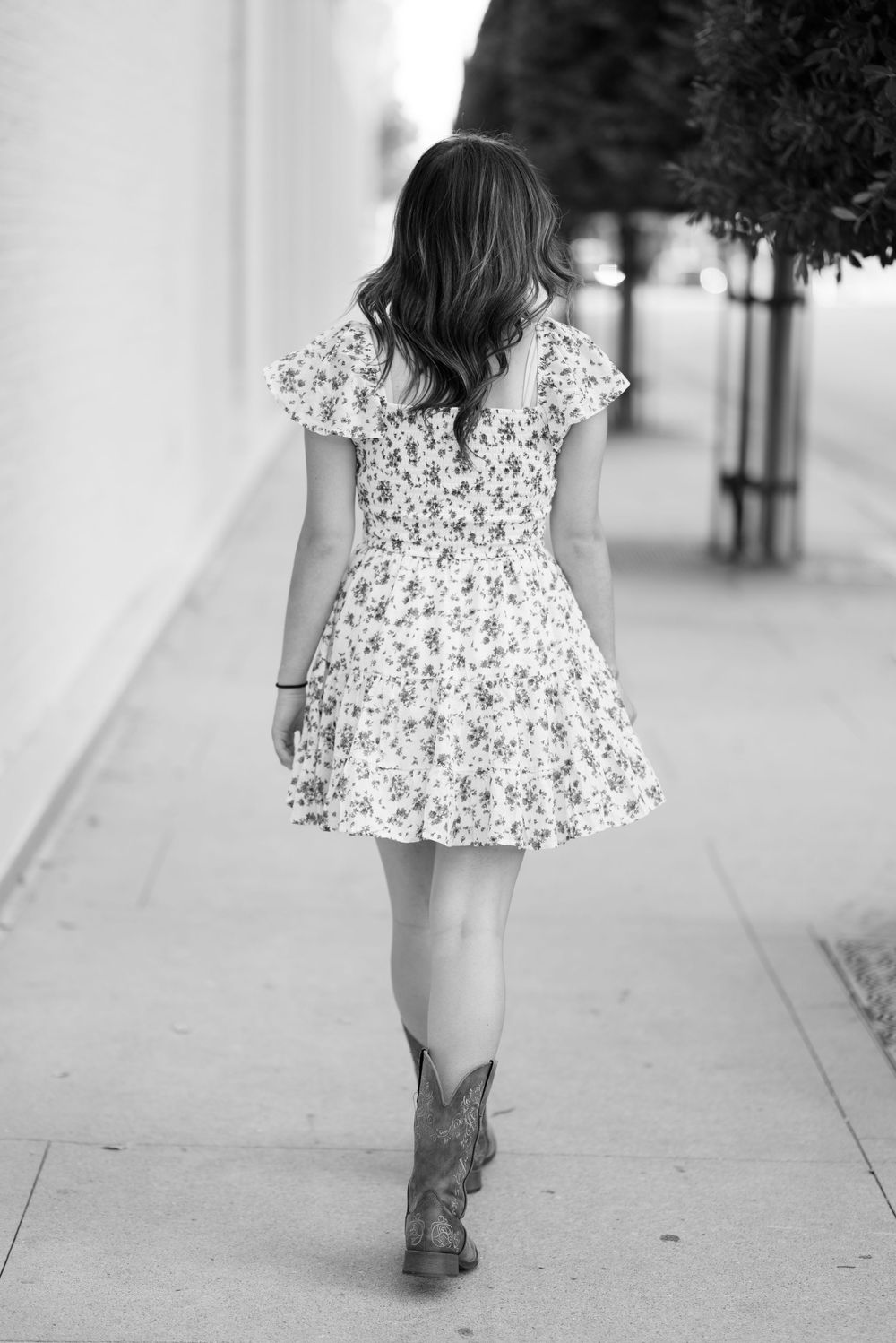Black and white photos showing someone in a floral dress and cowboy boots walking.