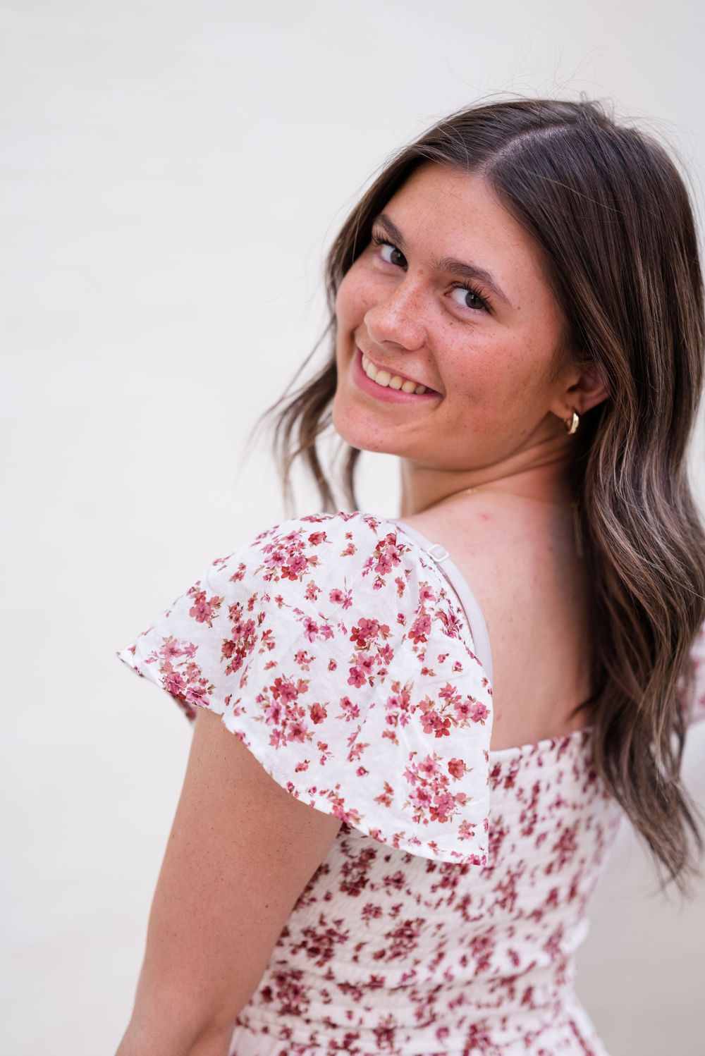 A close-up portrait showing a floral print dress with flutter sleeves against a light background.