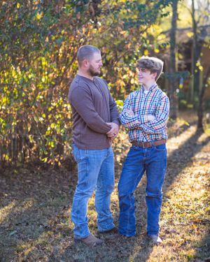 Two people having a conversation while standing in a wooded area with golden afternoon light.