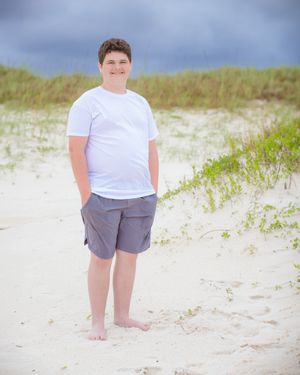 Casual beach portrait with sand dunes and stormy sky in background.