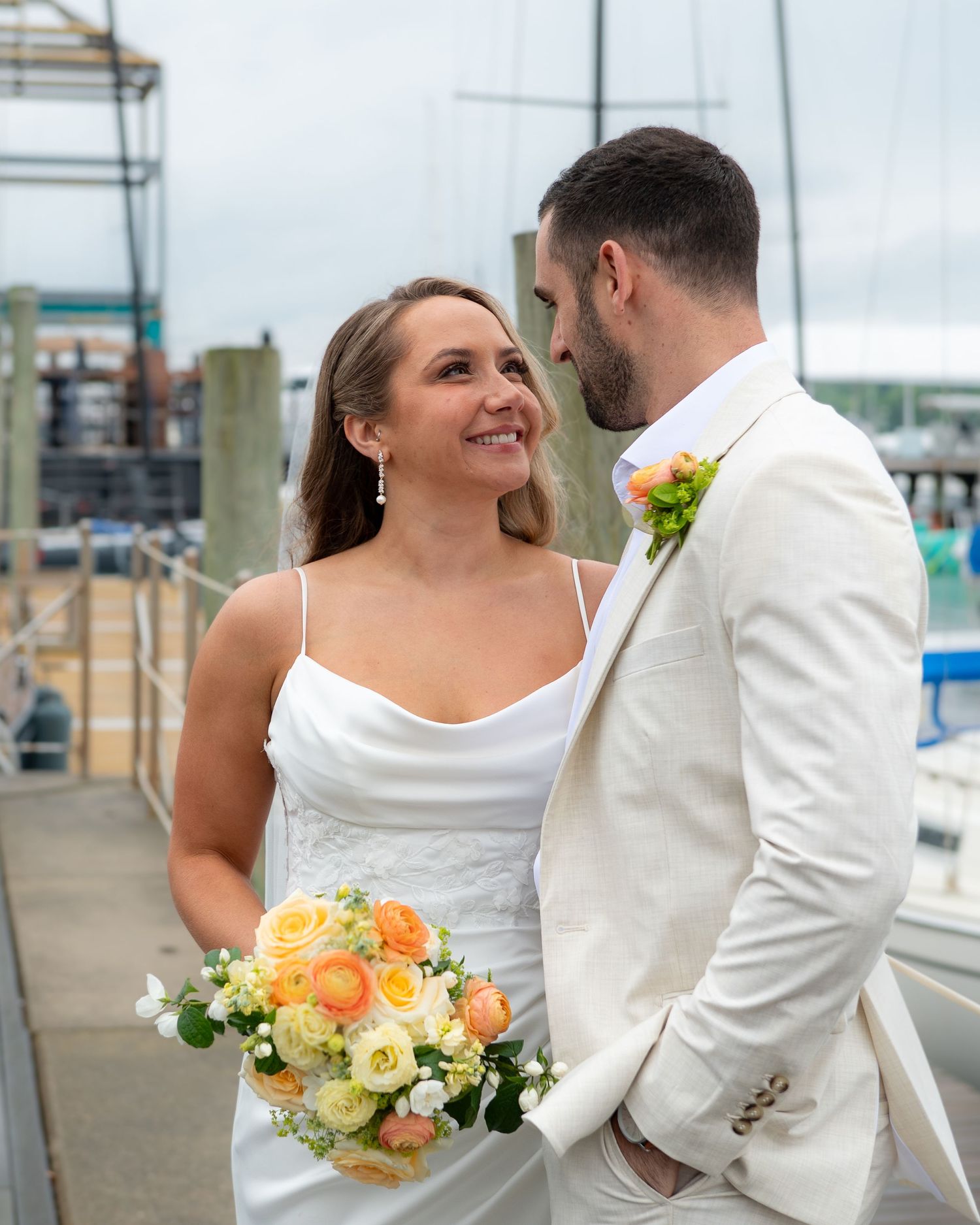 A romantic wedding couple shares intimate moments on a dock with yellow floral bouquet accents.