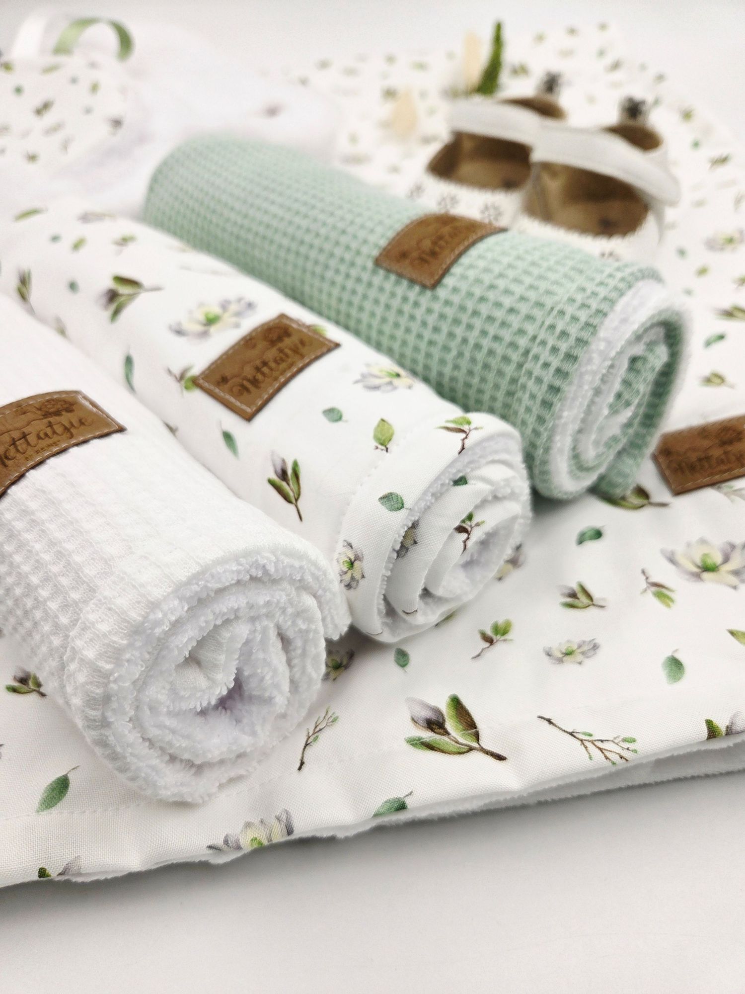 Mint green and white baby blankets with floral patterns and waffle textures displayed in a row.