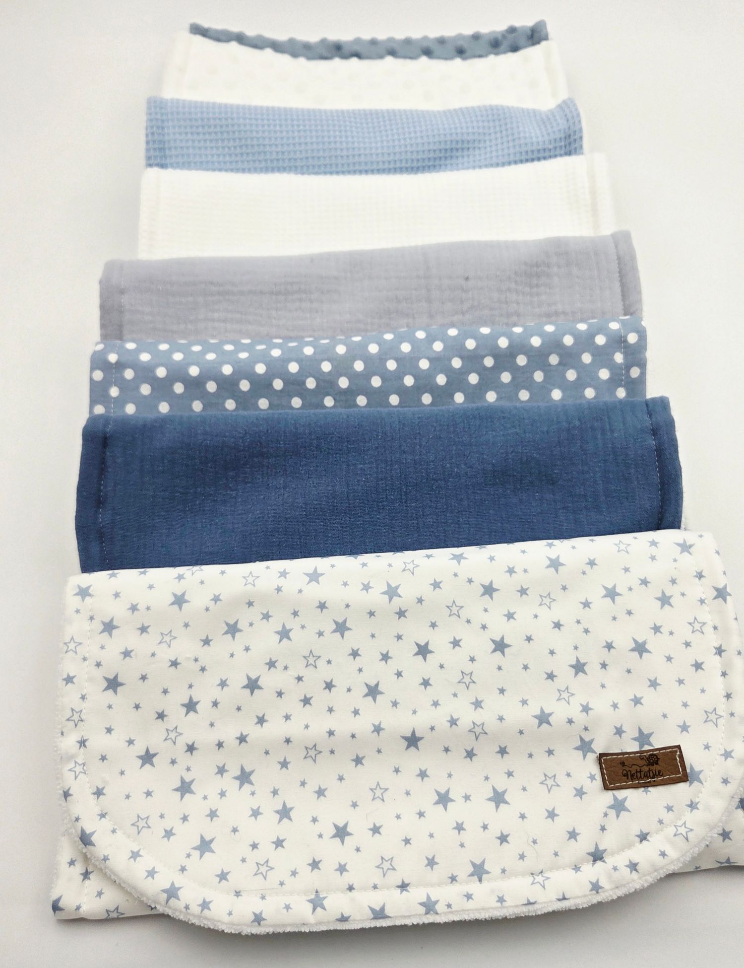 Blue and white baby blankets featuring polka dots, stars and stripes arranged in a layered display.