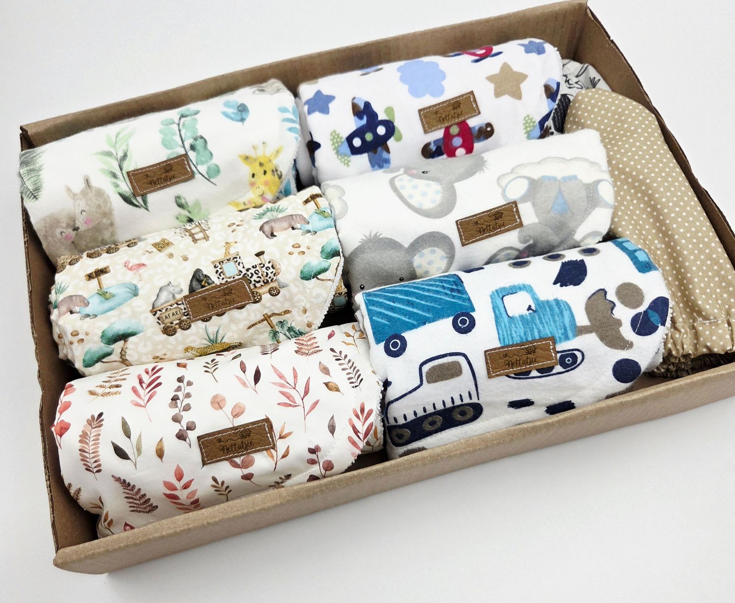 Baby blanket gift sets with vehicle and animal prints arranged in decorative boxes.