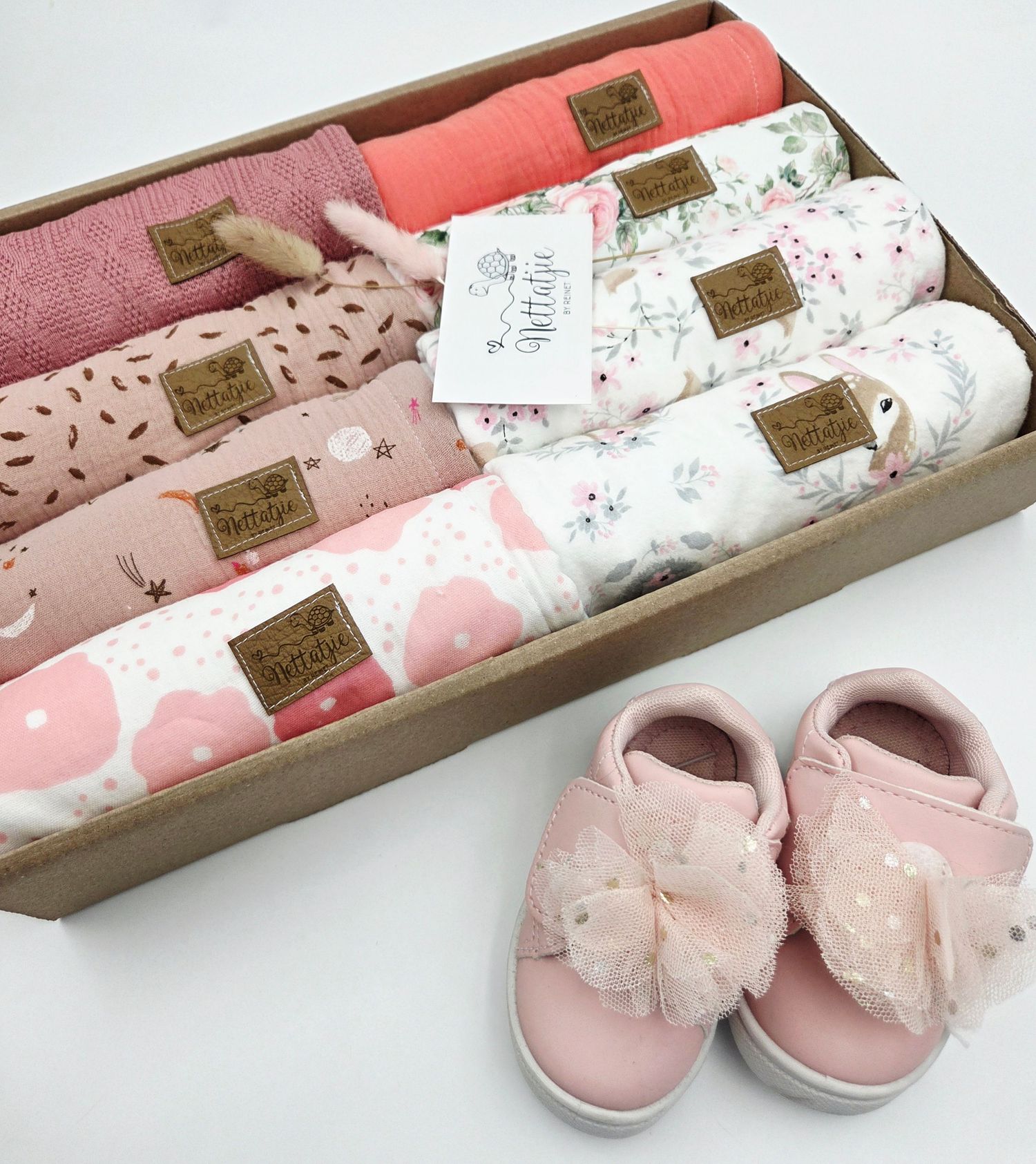 Collection of pink baby swaddle blankets with floral patterns and matching pink baby shoes.