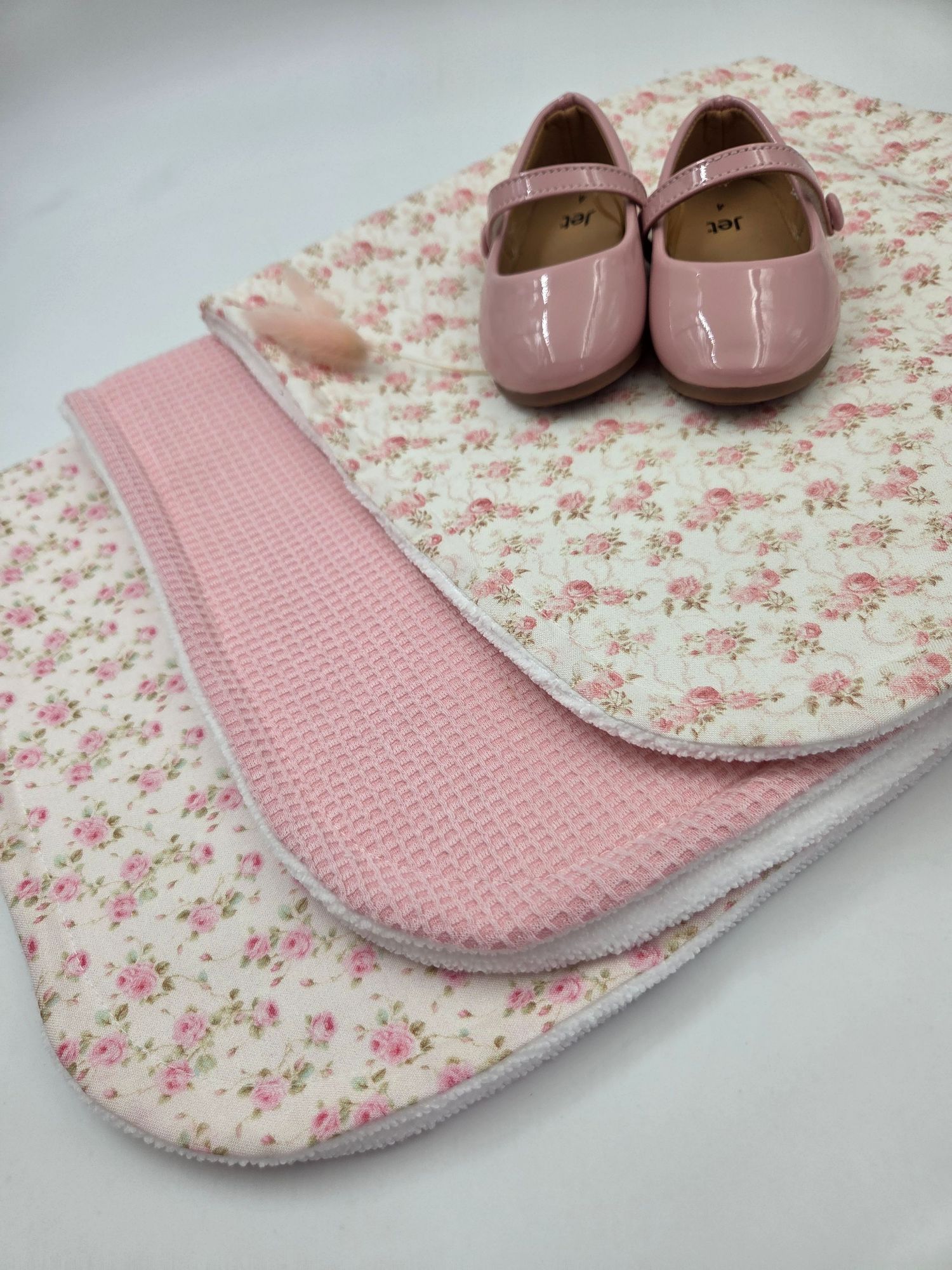 Pink floral burp cloth with matching patent leather baby shoes.