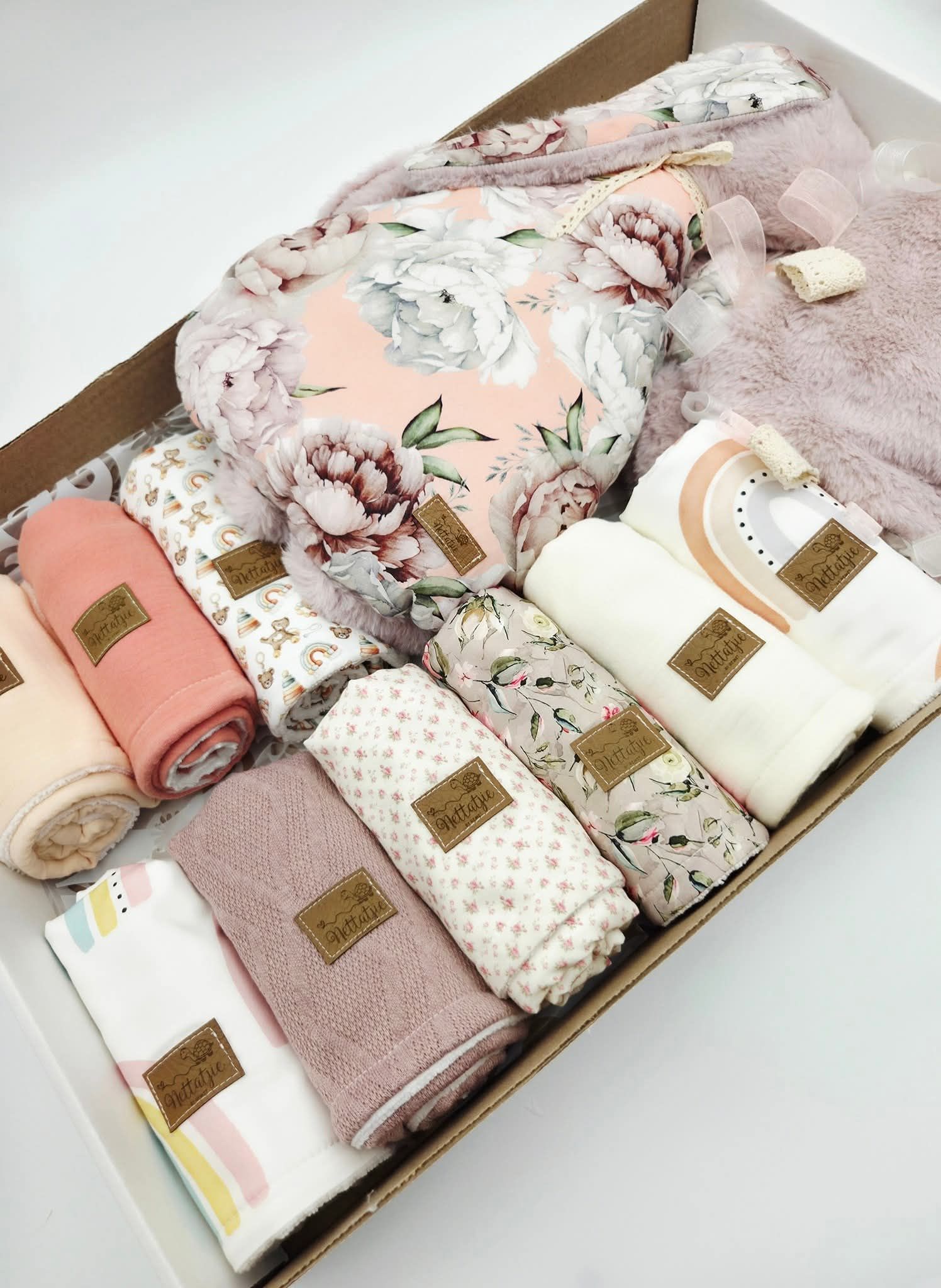 Box set of pink and white floral baby swaddle blankets with branded tags.