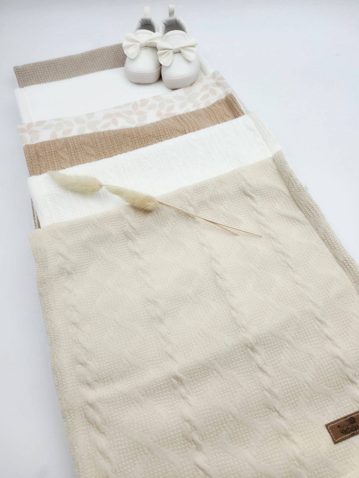 Neutral toned baby blanket with white and beige stripes and matching shoes.