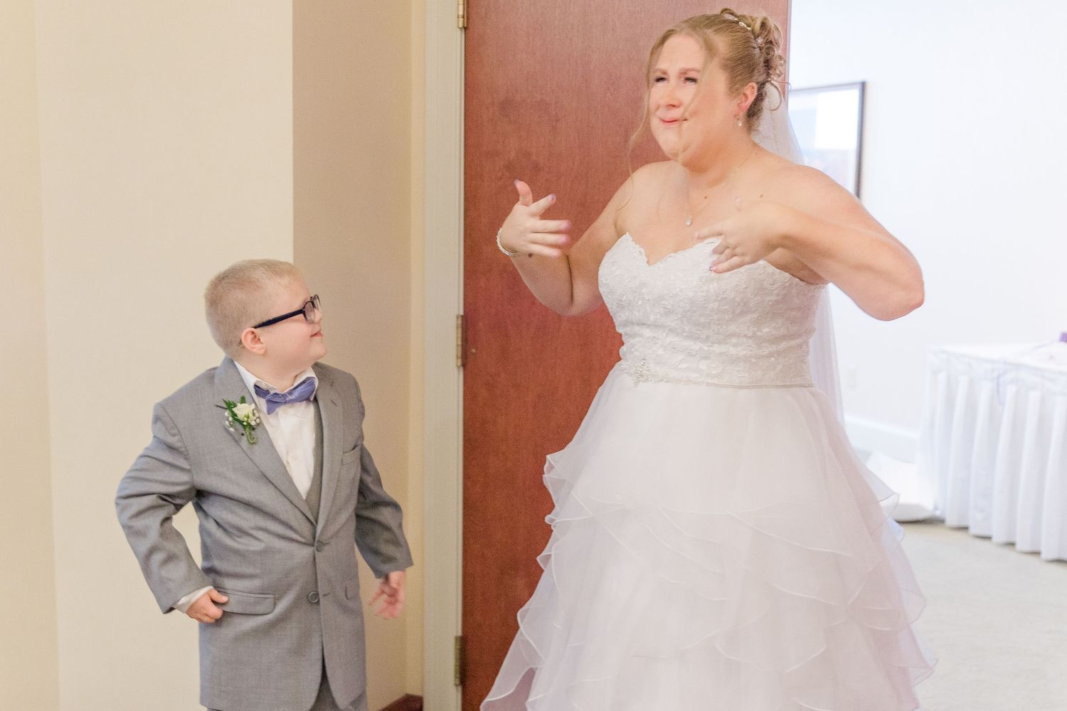 A playful moment between the bride and a young ring bearer in a bowtie.