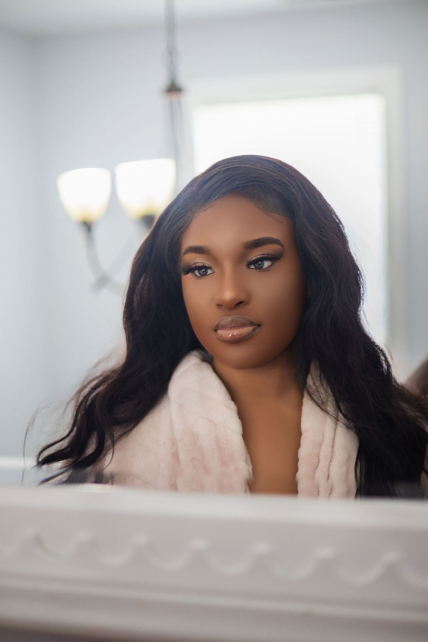 Elegant mirror reflection portrait featuring flawless makeup and soft waves.