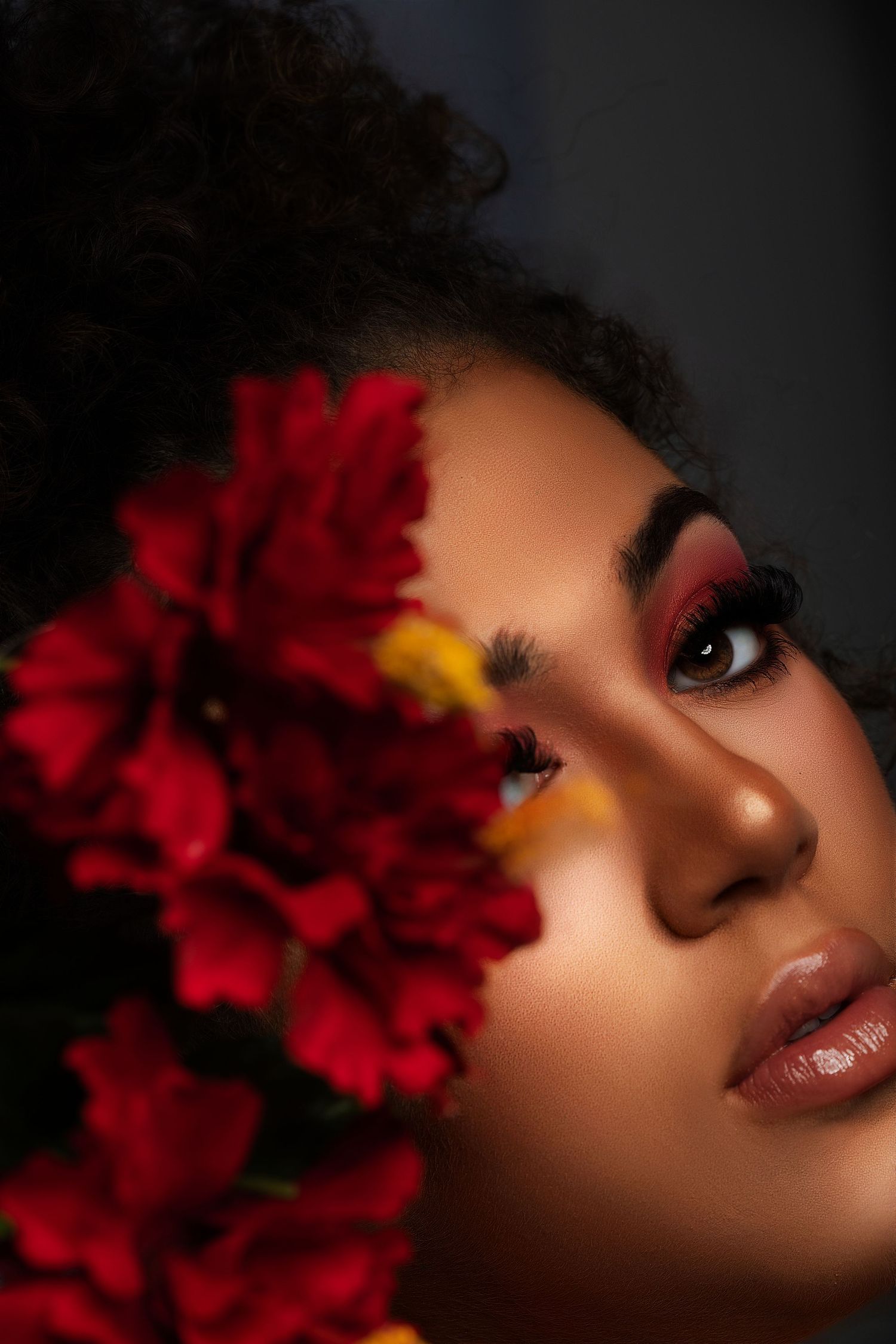 Artistic beauty portrait with dramatic red flowers and matching eye makeup.