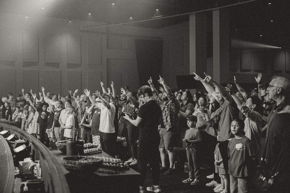 Black and white panoramic photo showing a large crowd of people dancing at a formal event in an elegant ballroom.