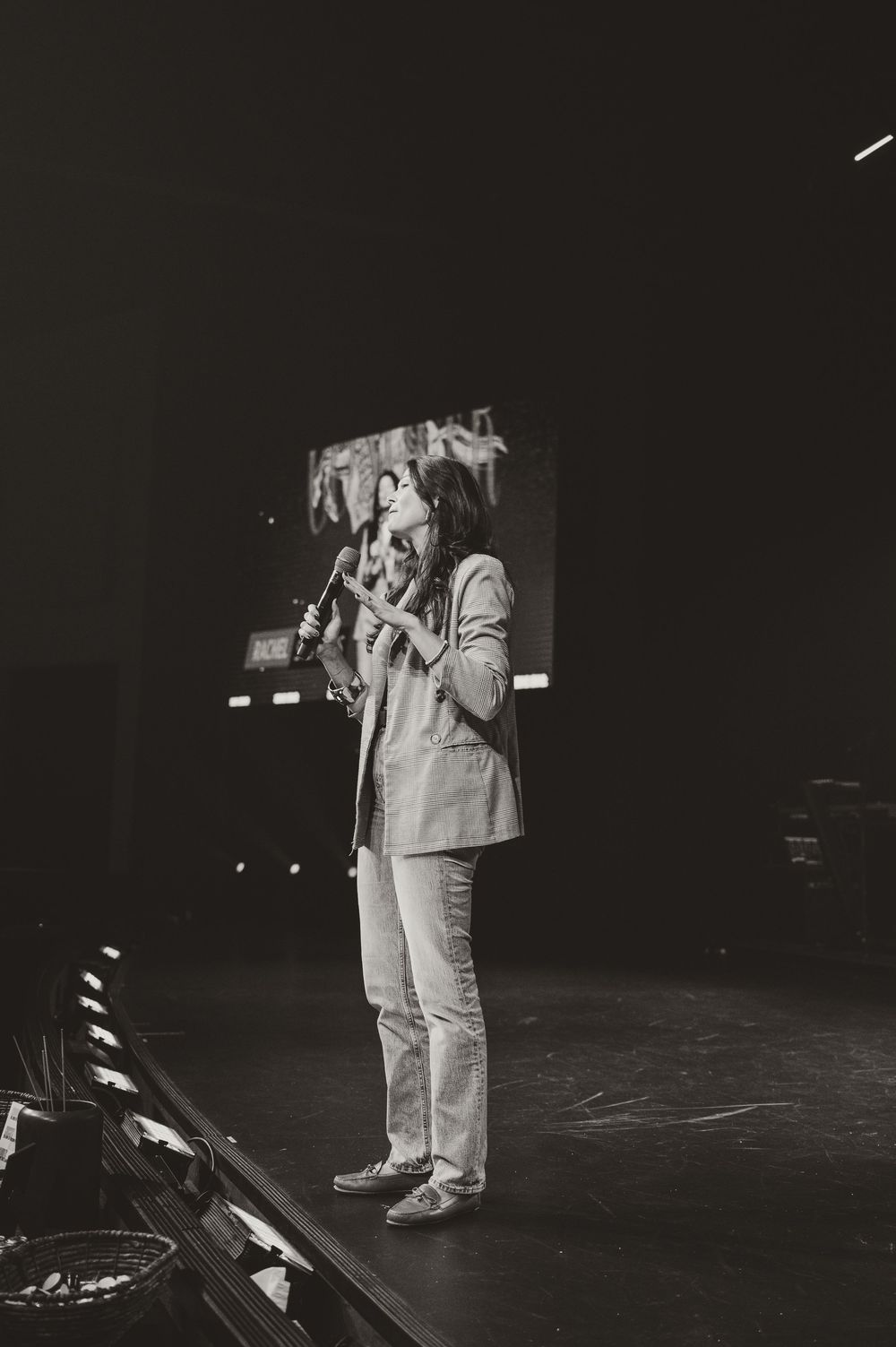 A black and white photo series shows a person in light-colored clothing standing on stage in a dark performance space.