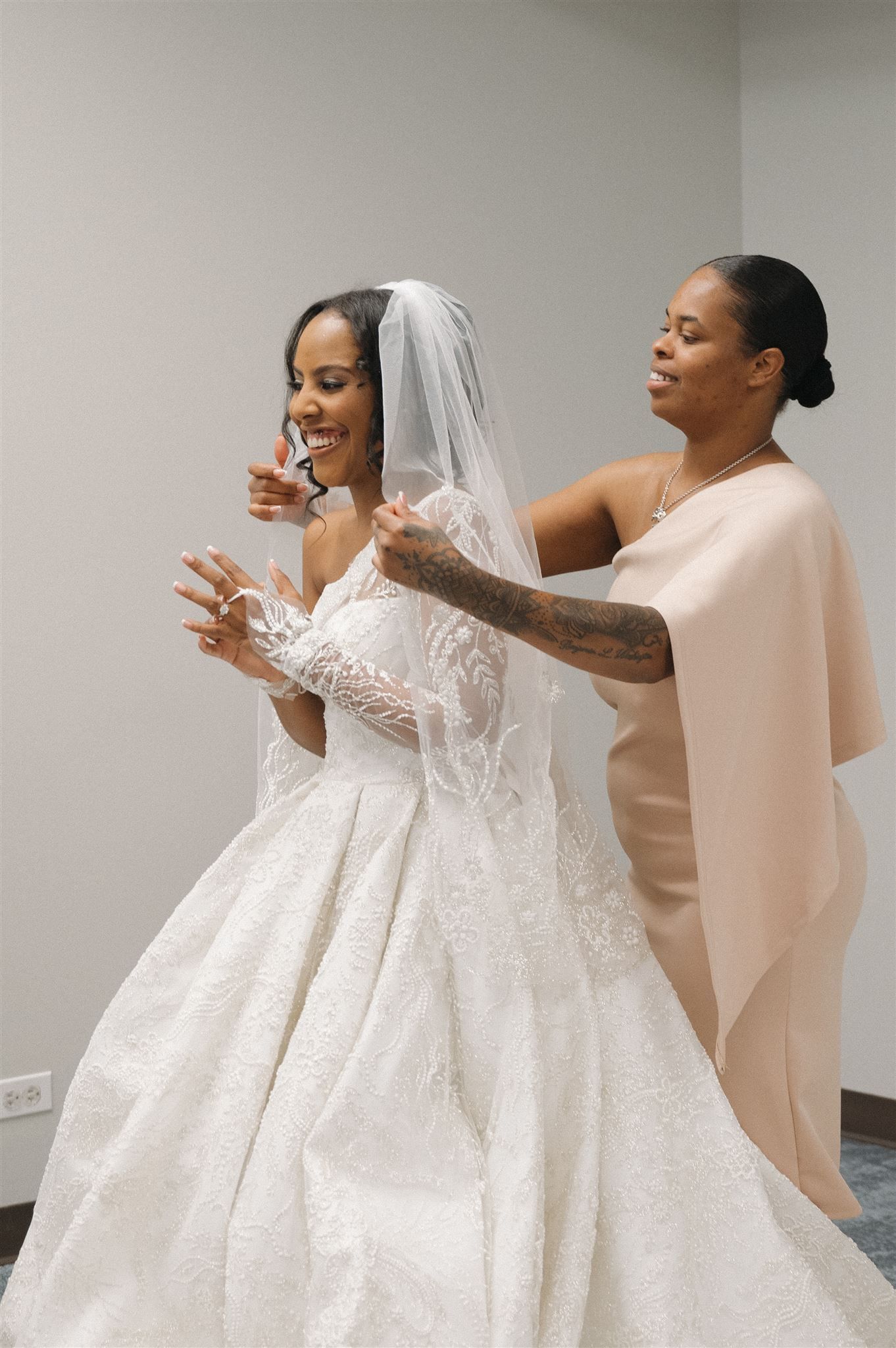 Wedding dress fitting session showing final adjustments and veil placement.