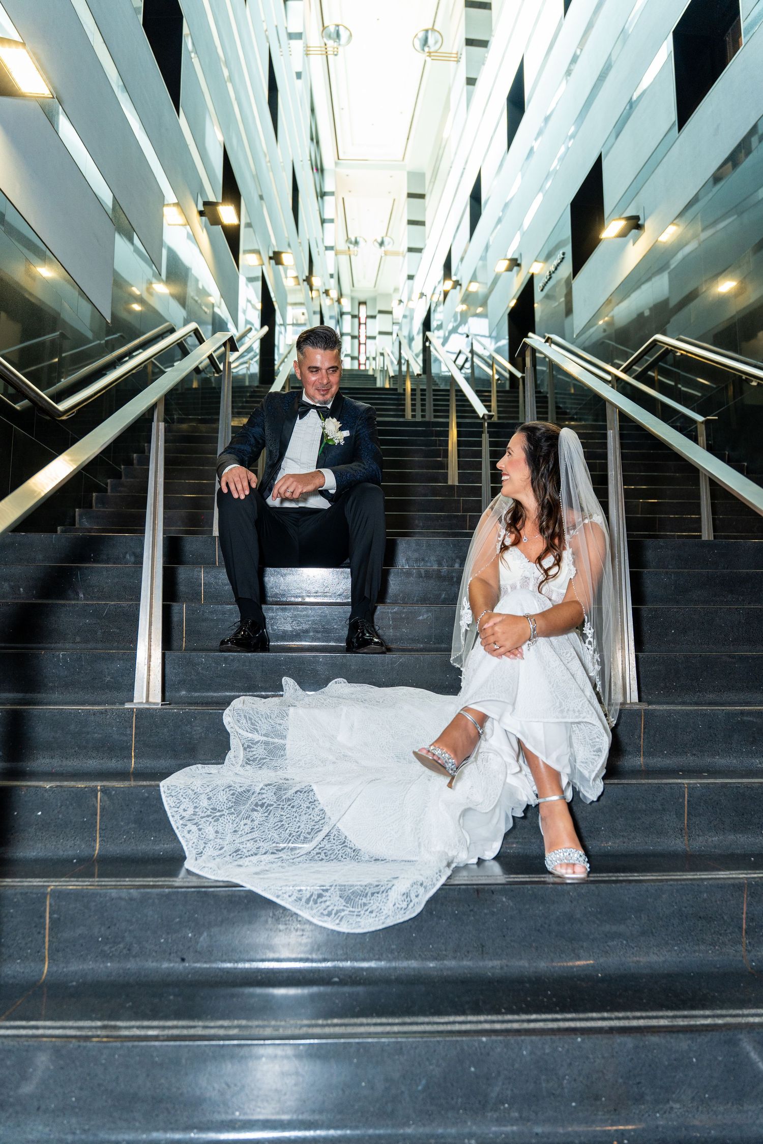 Artistic wedding photo series showing couple posing playfully on modern staircase with geometric white architecture.