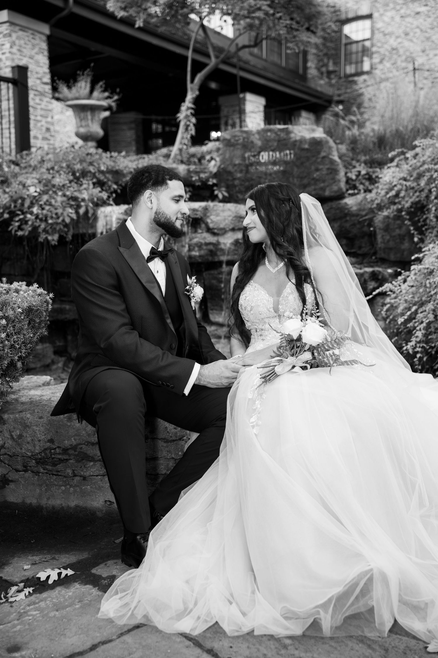 A romantic black and white wedding photo series showing tender moments between newlyweds in an outdoor garden setting.