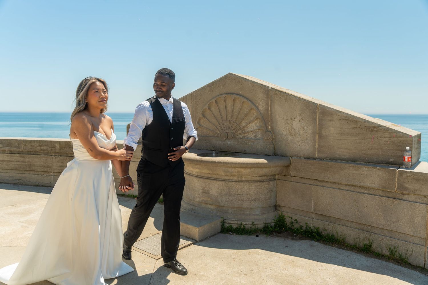 A wedding couple dances gracefully along a stone balcony with ocean views.