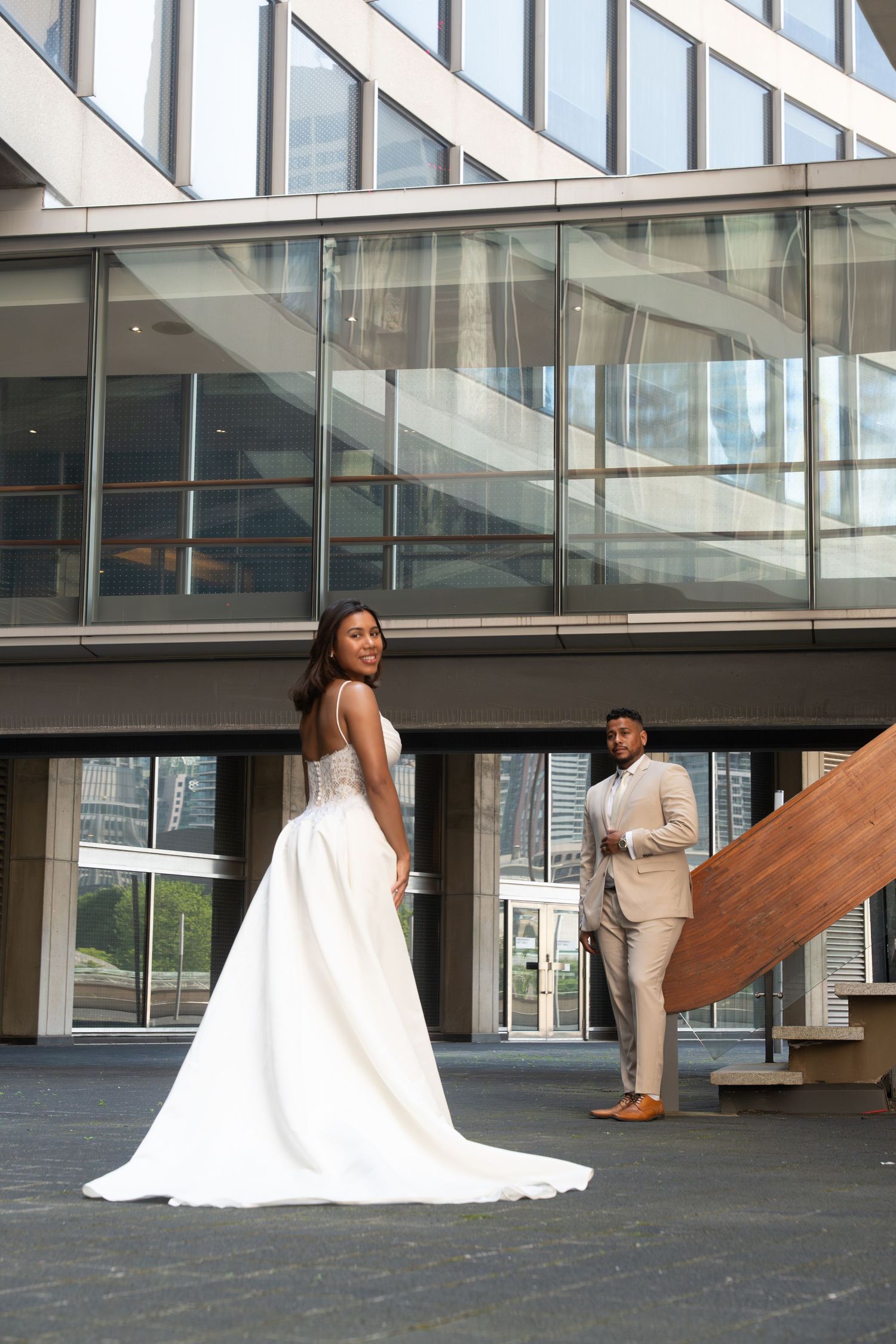 A series of artistic fashion photos showing two models in white and beige outfits posing in a modern glass building.