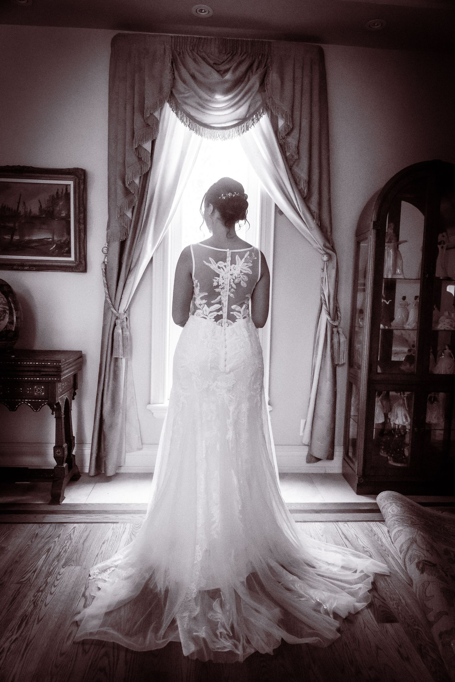 A series of black and white photos showing the back details of a wedding dress with delicate lace and flowing train.