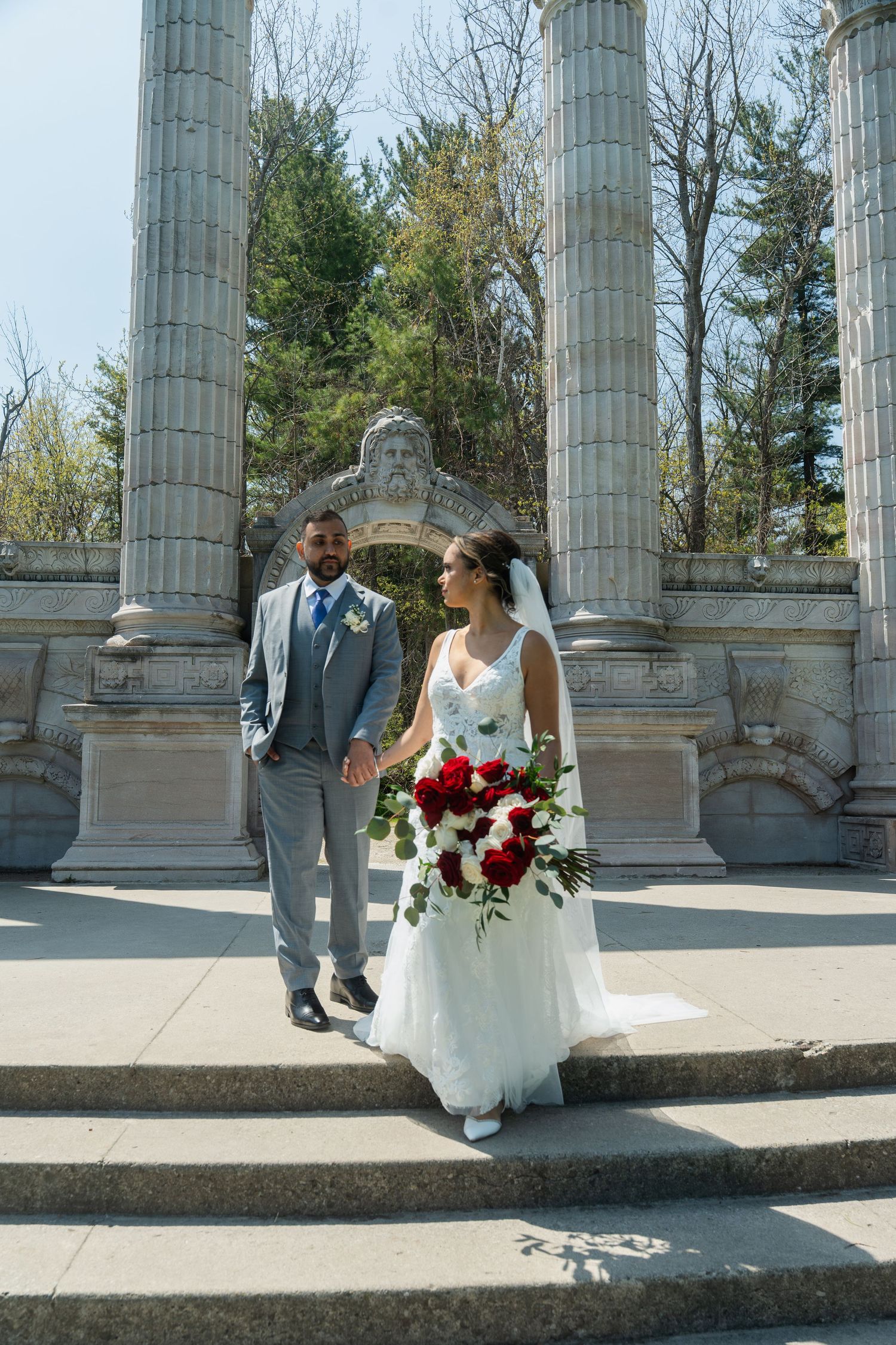 Romantic wedding portraits captured at a classical stone colonnade during springtime.
