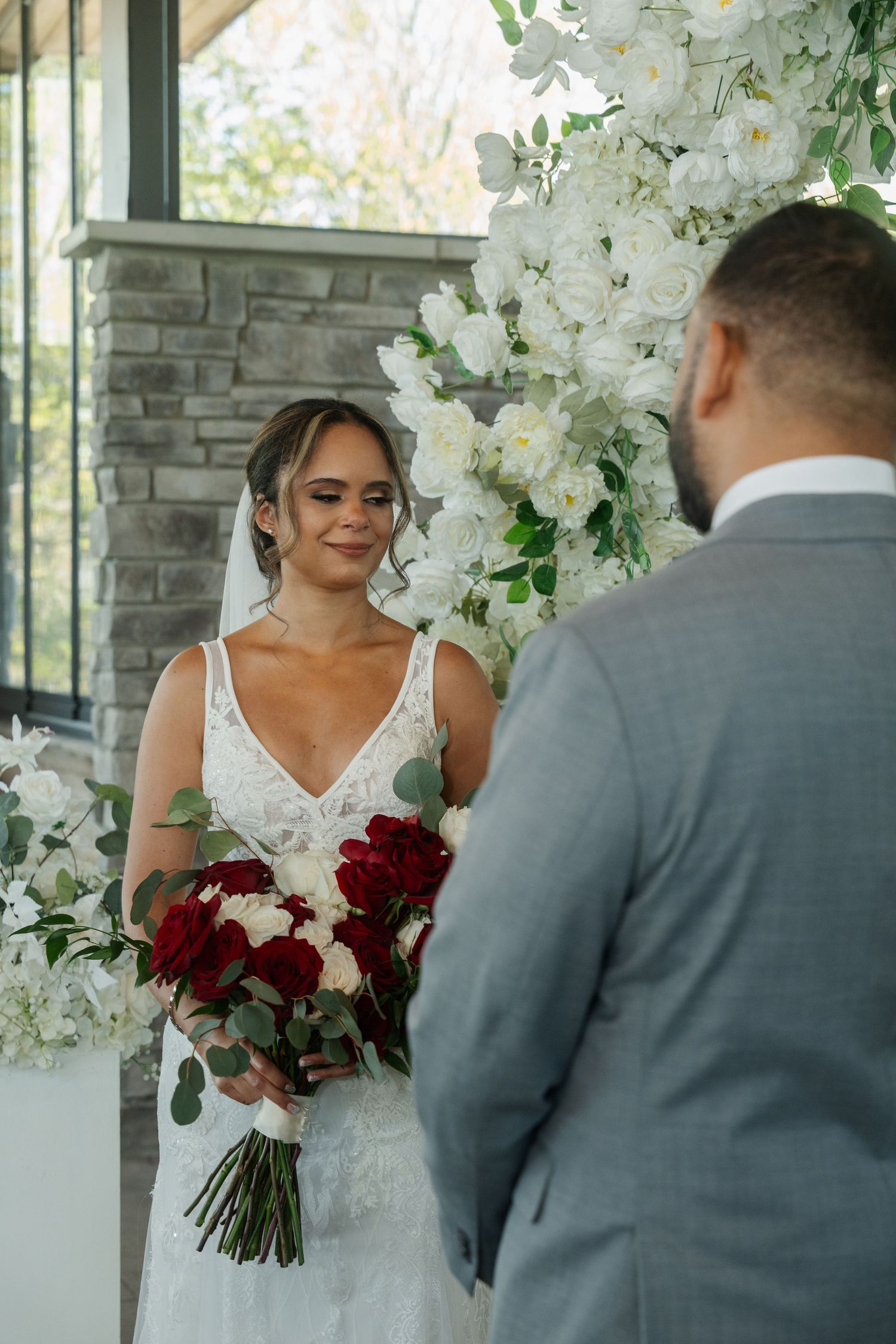Indoor wedding photos with elegant white floral arrangements and red rose bouquet.