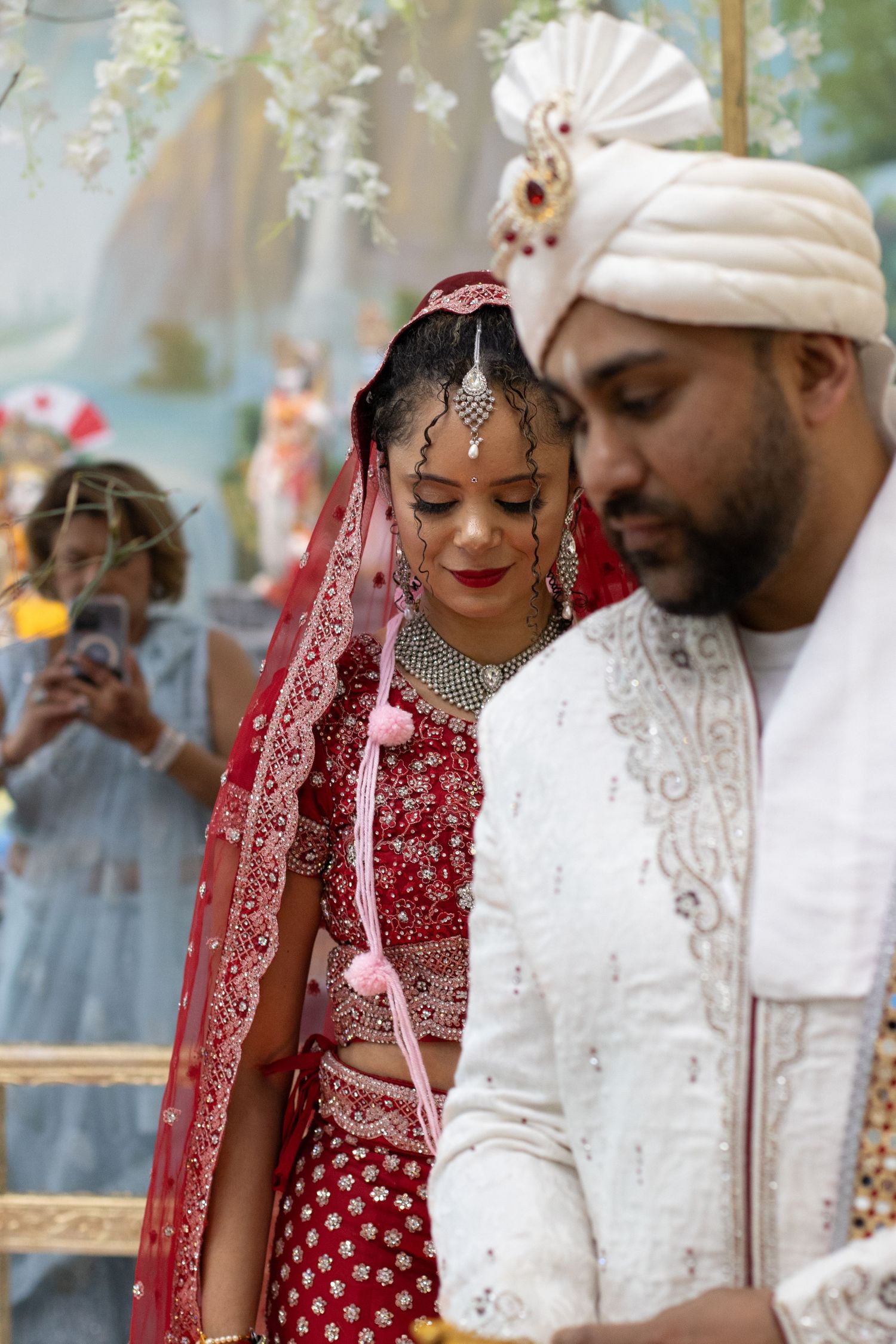 Couple in traditional Indian wedding outfits share a tender moment during their ceremony.
