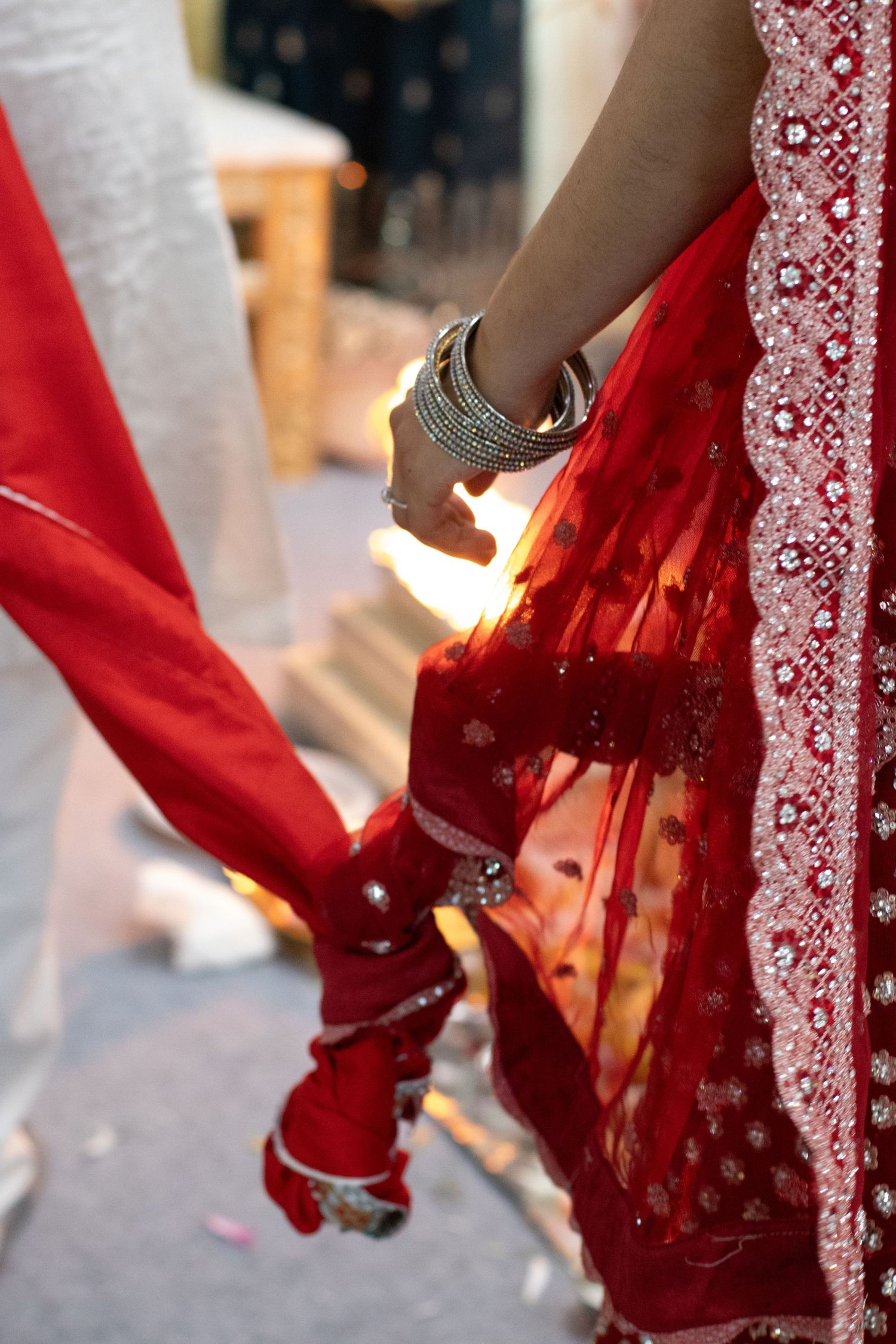 Close-up of flowing red wedding sari with intricate embroidery and detailing.