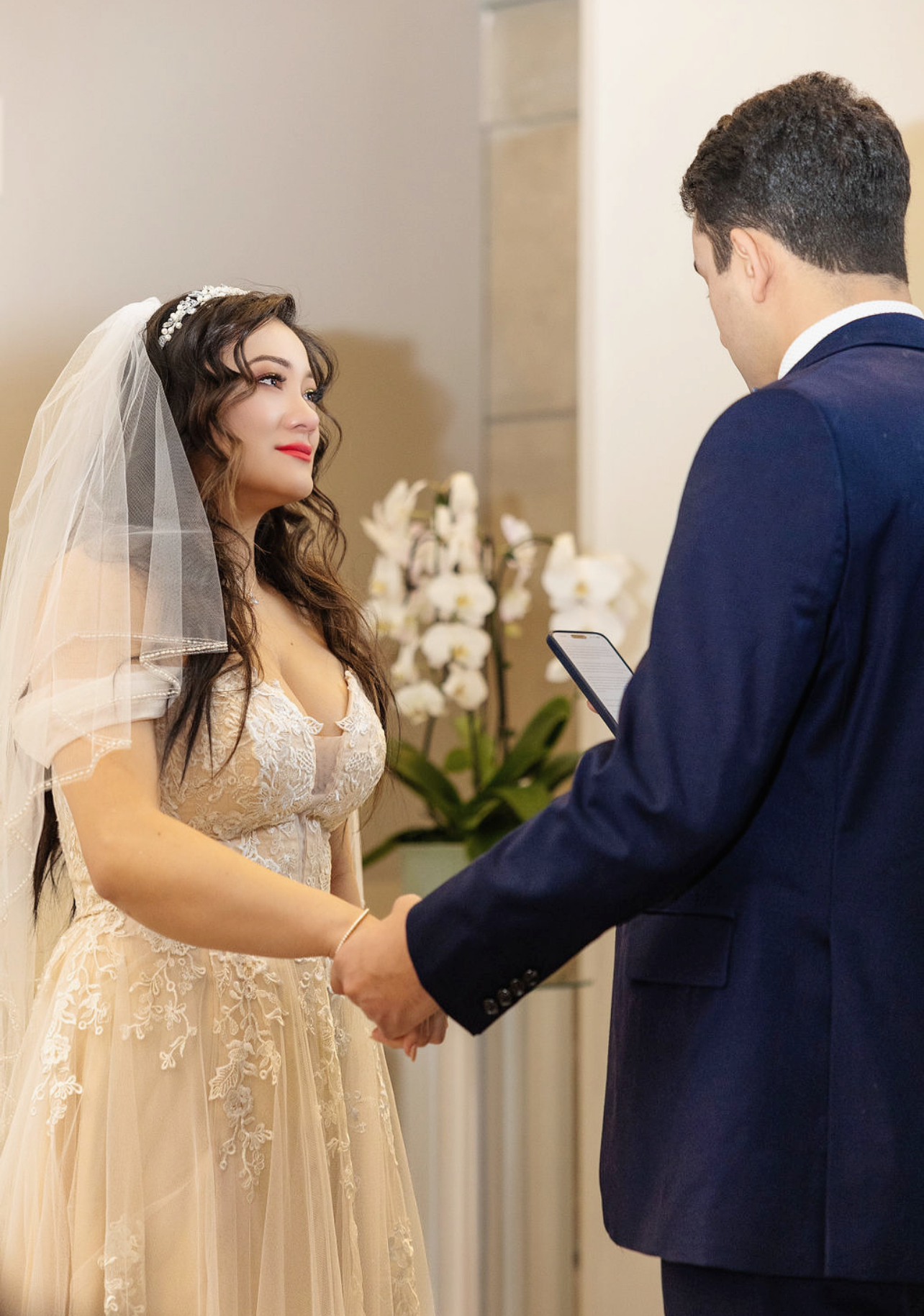 A couple in formal wedding attire shares an intimate moment indoors.