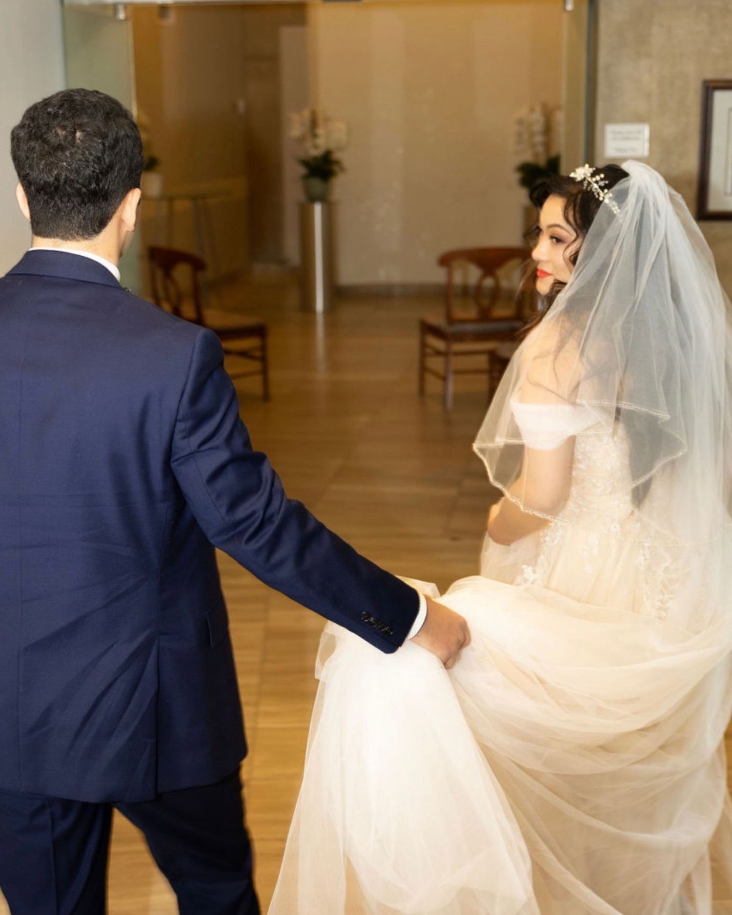 Flowing white wedding veil billows gracefully behind couple during romantic photo session.