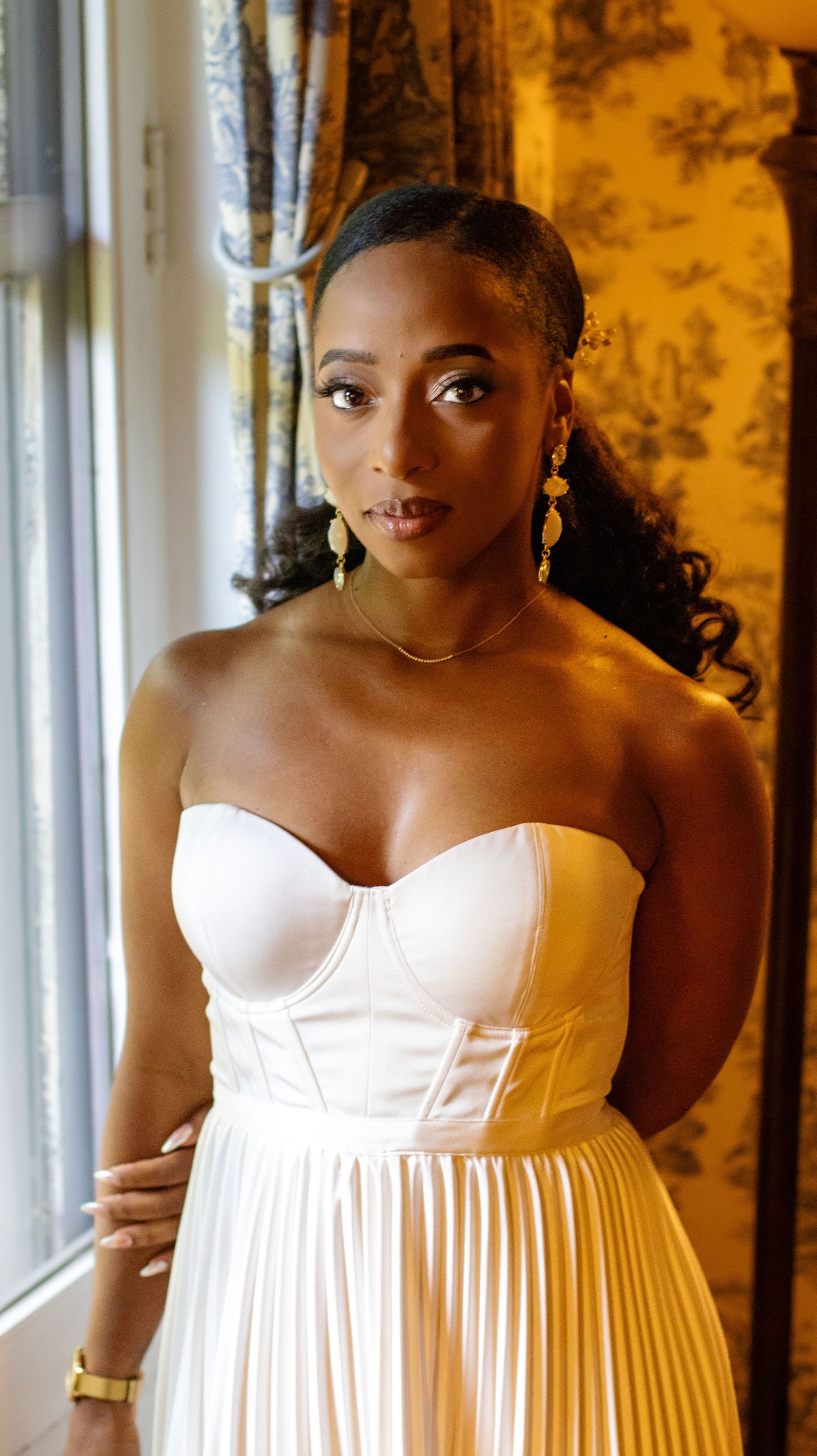 Beautiful wedding portraits showing bride in white strapless dress against warm golden backdrop.