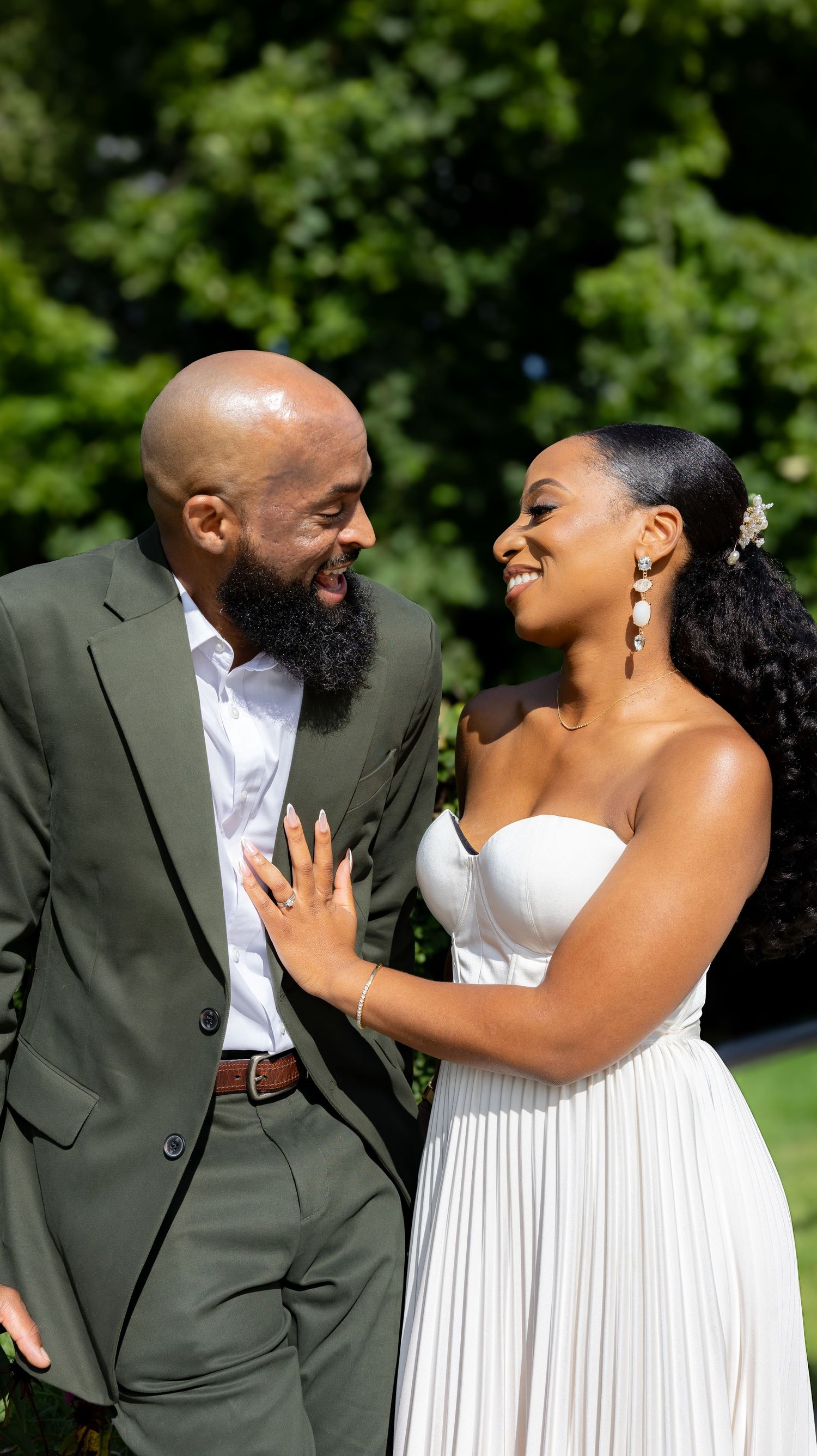 Joyful candid moments between couple laughing together during outdoor wedding photoshoot.