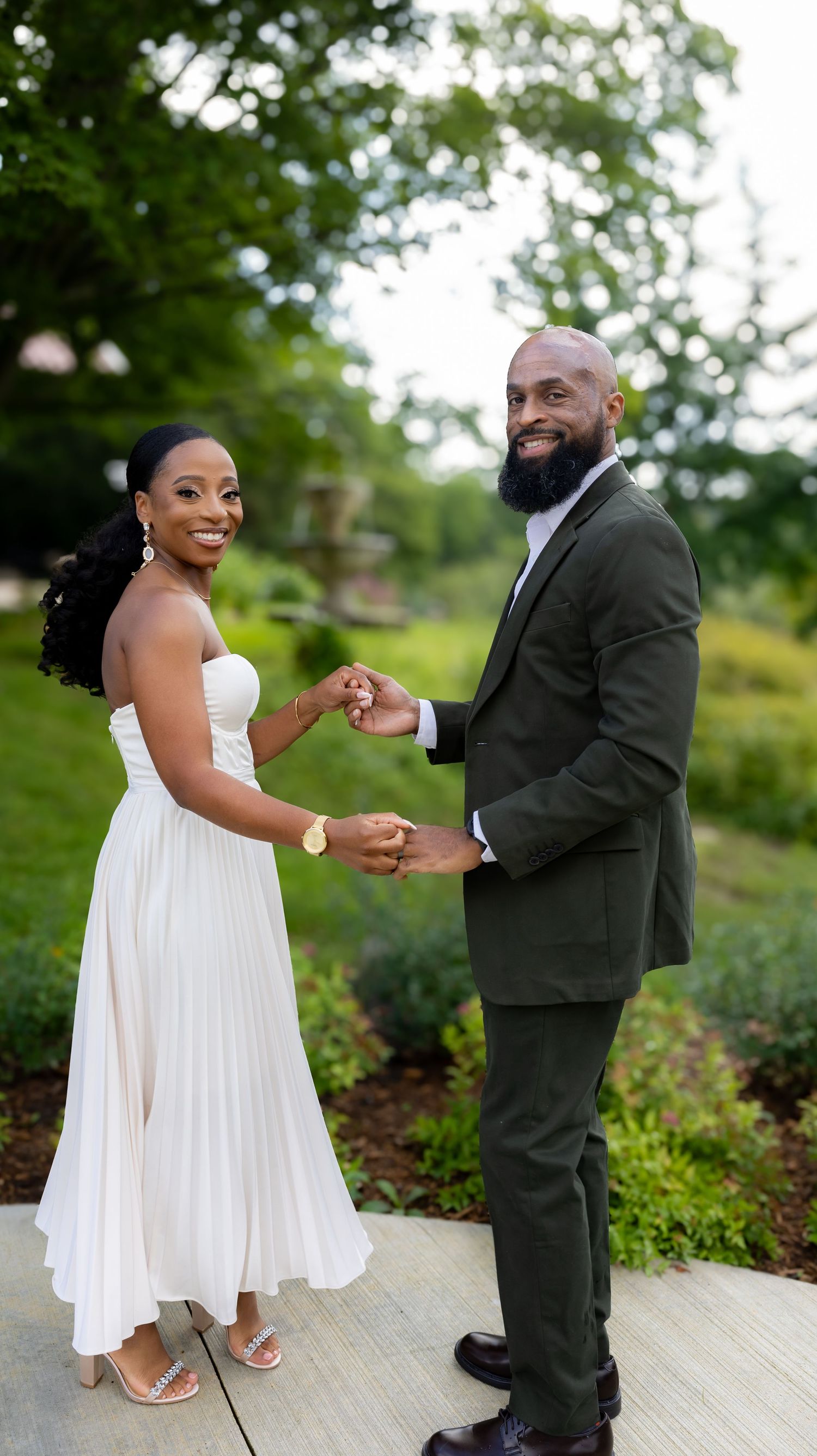 Playful dancing sequence of newlyweds on stone path surrounded by garden greenery.