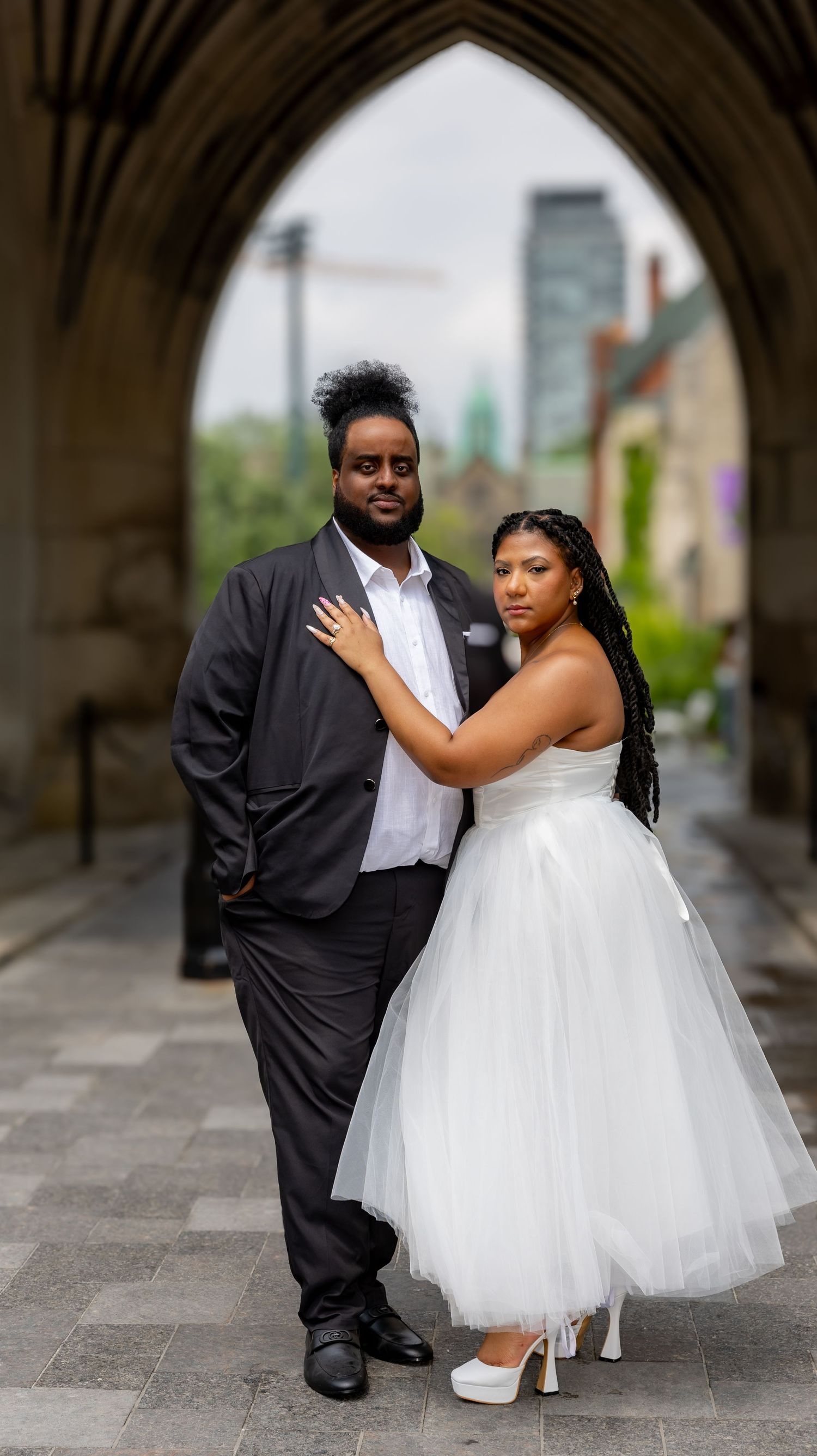 A romantic wedding photo series showing a couple in formal attire posing together under an arched walkway.