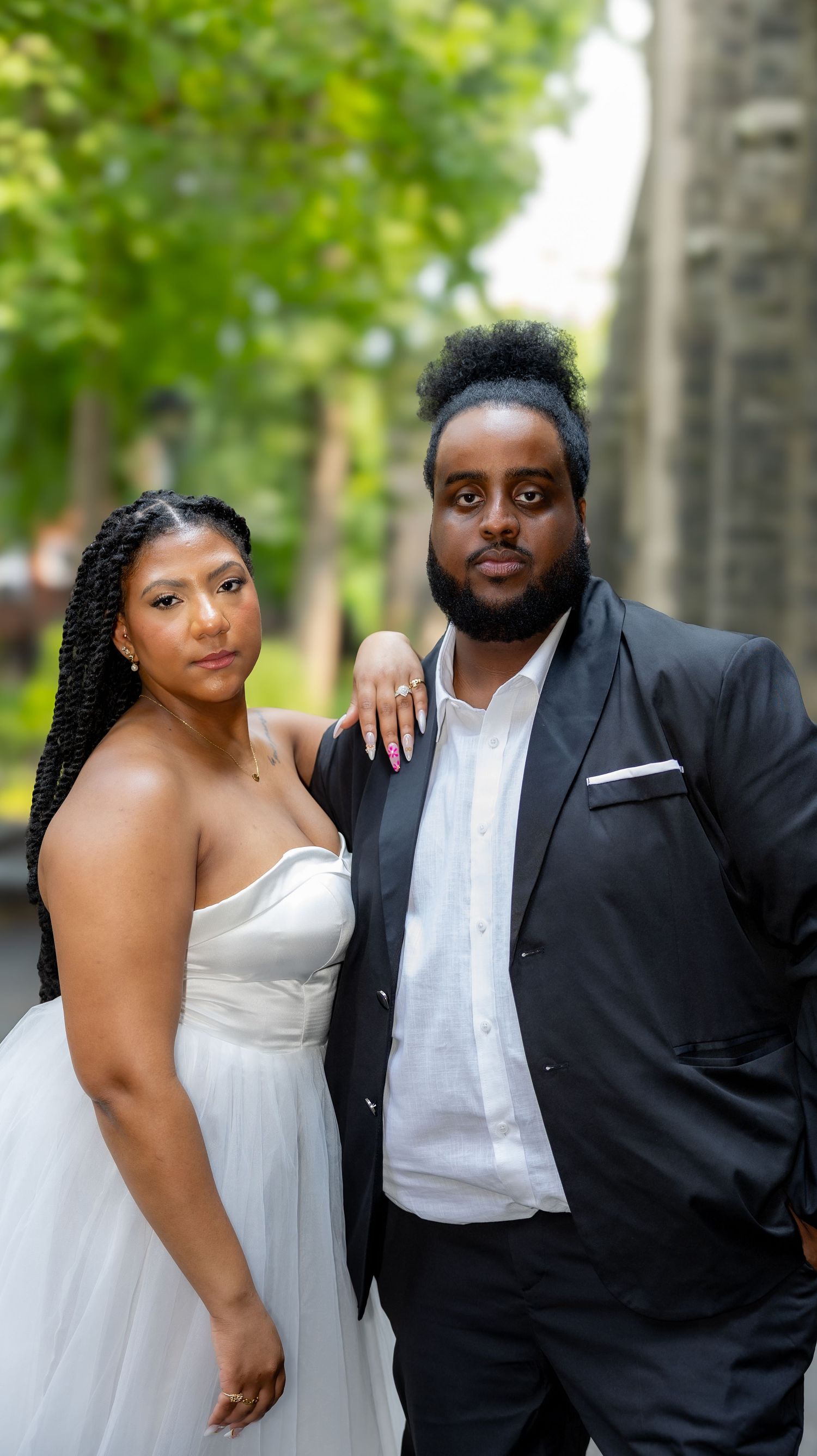 Elegant wedding portraits of a couple in white and black formal wear outdoors with greenery in background.