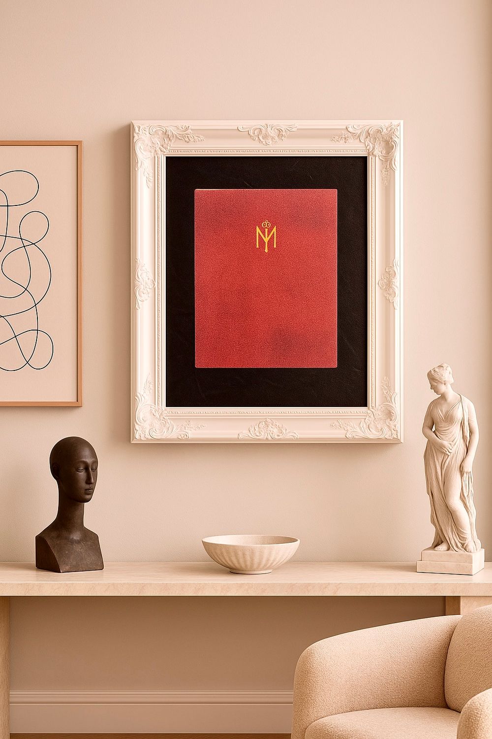 Modern art display featuring a red book with gold monogram in ornate white frame, alongside sculptural busts and abstract artwork.