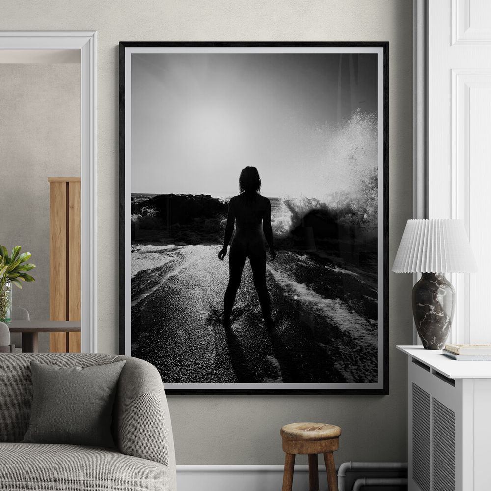 A dramatic black and white photograph of a silhouette standing on a wet road against bright backlighting.