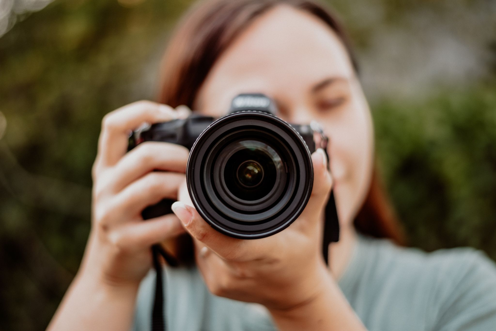 Close-up of photographer taking picture with professional camera lens.