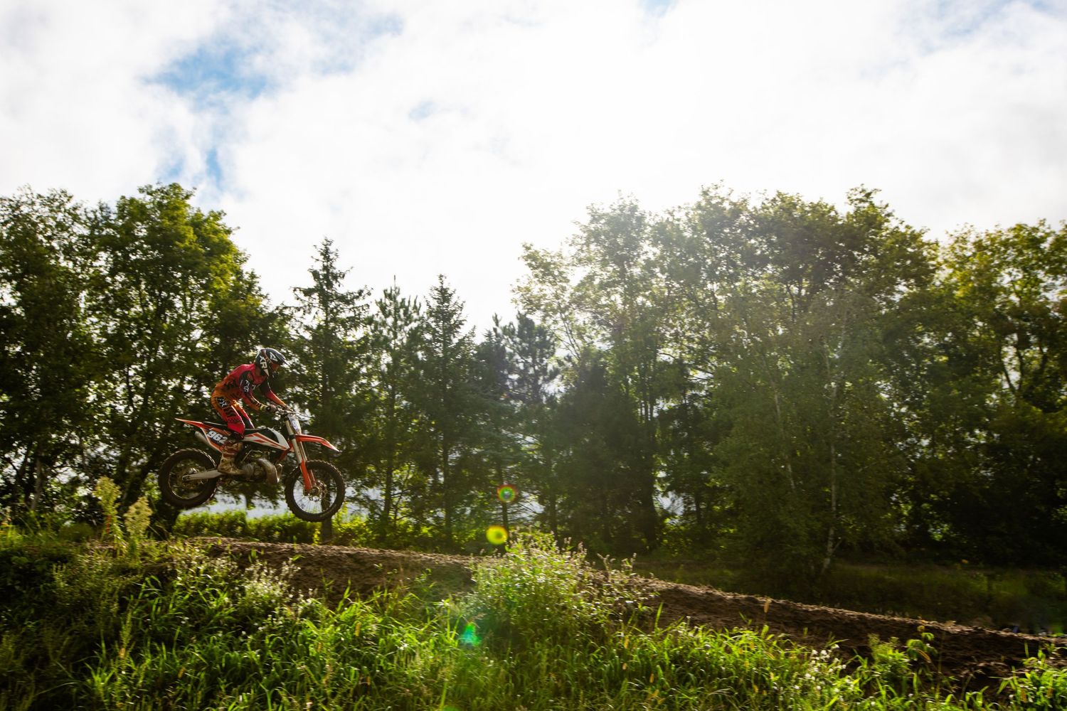 Scenic motocross track panorama with trees and cloudy sky in natural lighting.