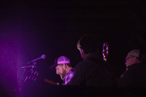 Concert venue with purple stage lighting and silhouetted performers.