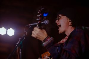 Live music performance in dark venue with atmospheric stage lighting.
