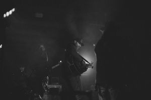 Dark concert venue with dramatic stage lighting and silhouetted performers.