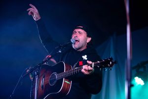Musicians performing on stage with blue lighting and acoustic guitar setup.