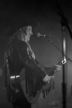 Silhouetted performer strumming guitar in moody stage lighting.