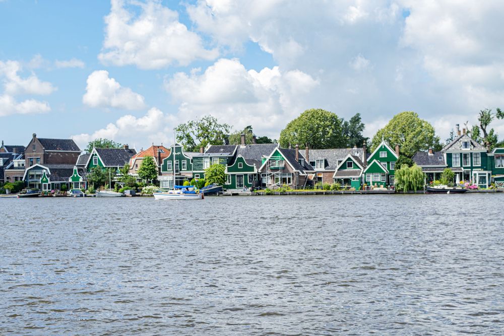 Colorful traditional Dutch houses line the waterfront of a canal on a sunny day in the Netherlands.