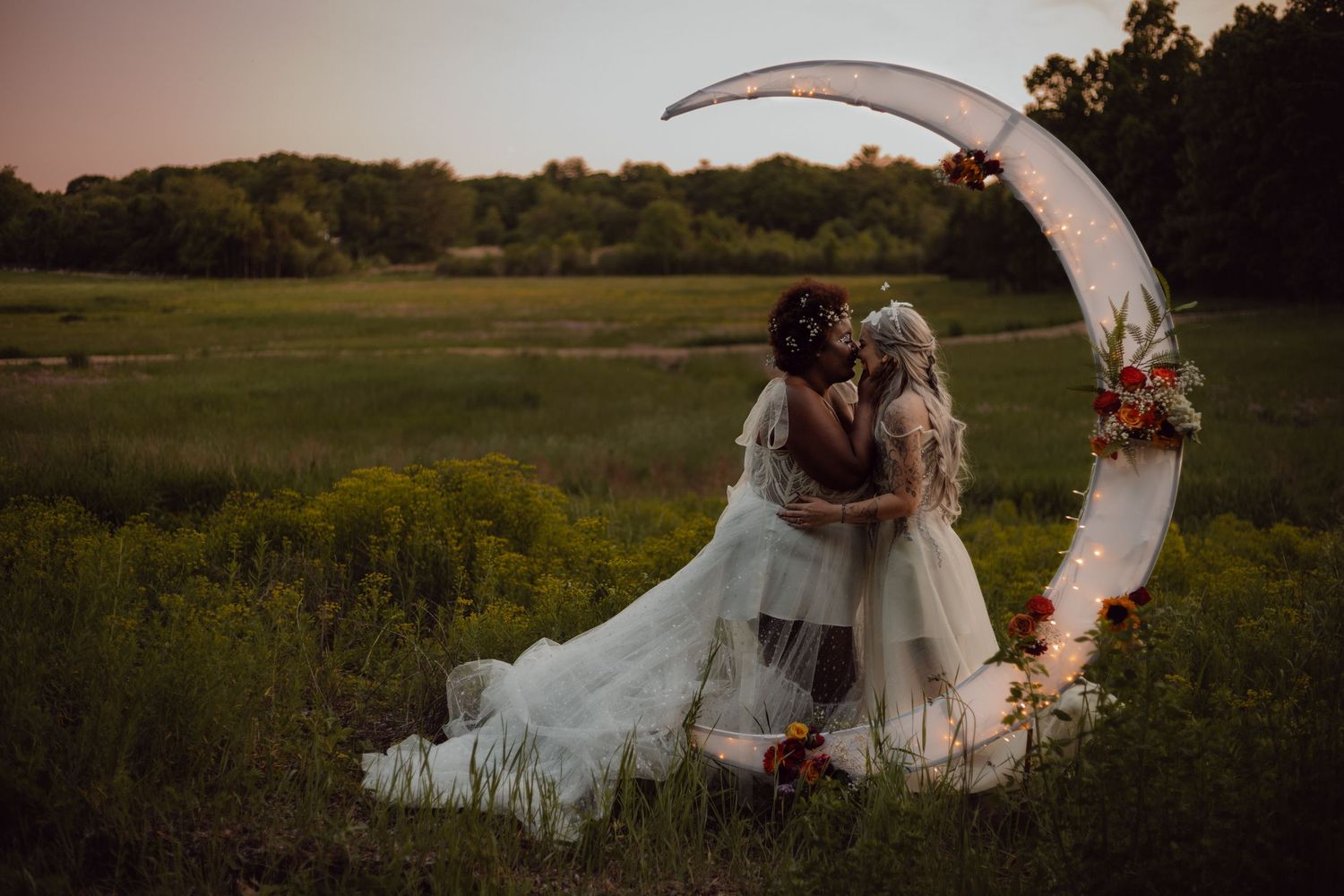 An first kiss shared in front of a mystical crescent moon backdrop. Sun set elopement. Lesbian wedding photographer.