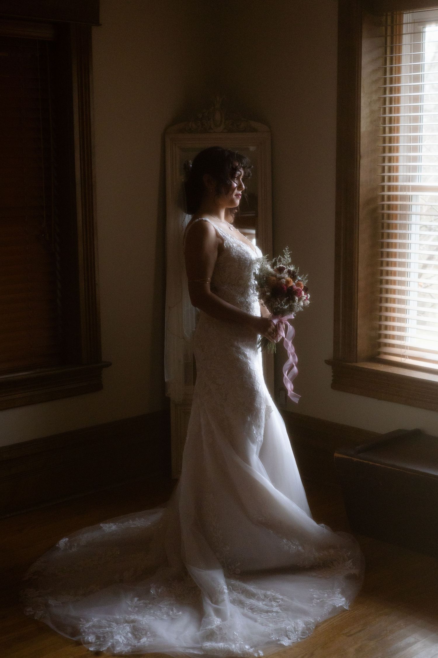An ethereal portrait of the bride staring out the window fully ready to meet the groom for a first look. Soft light pouring in.