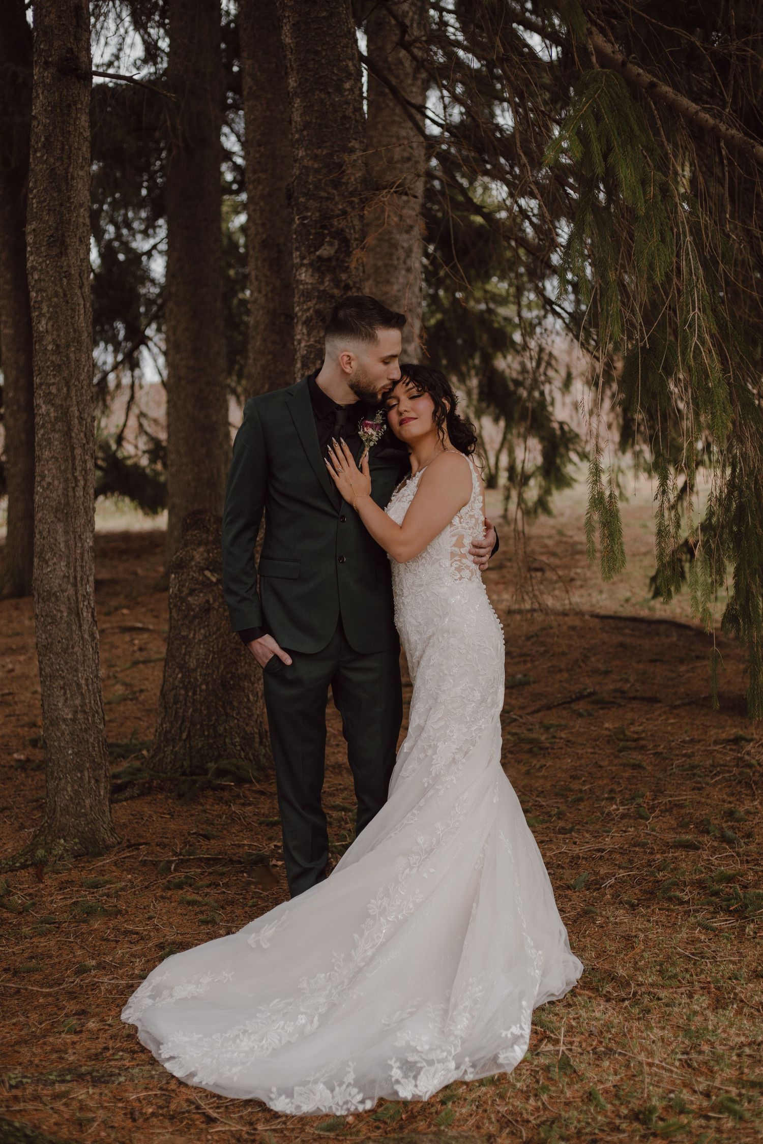 A bride and groom portrait under a family of evergreen trees at Cambium Farms, Ontario wedding venue.