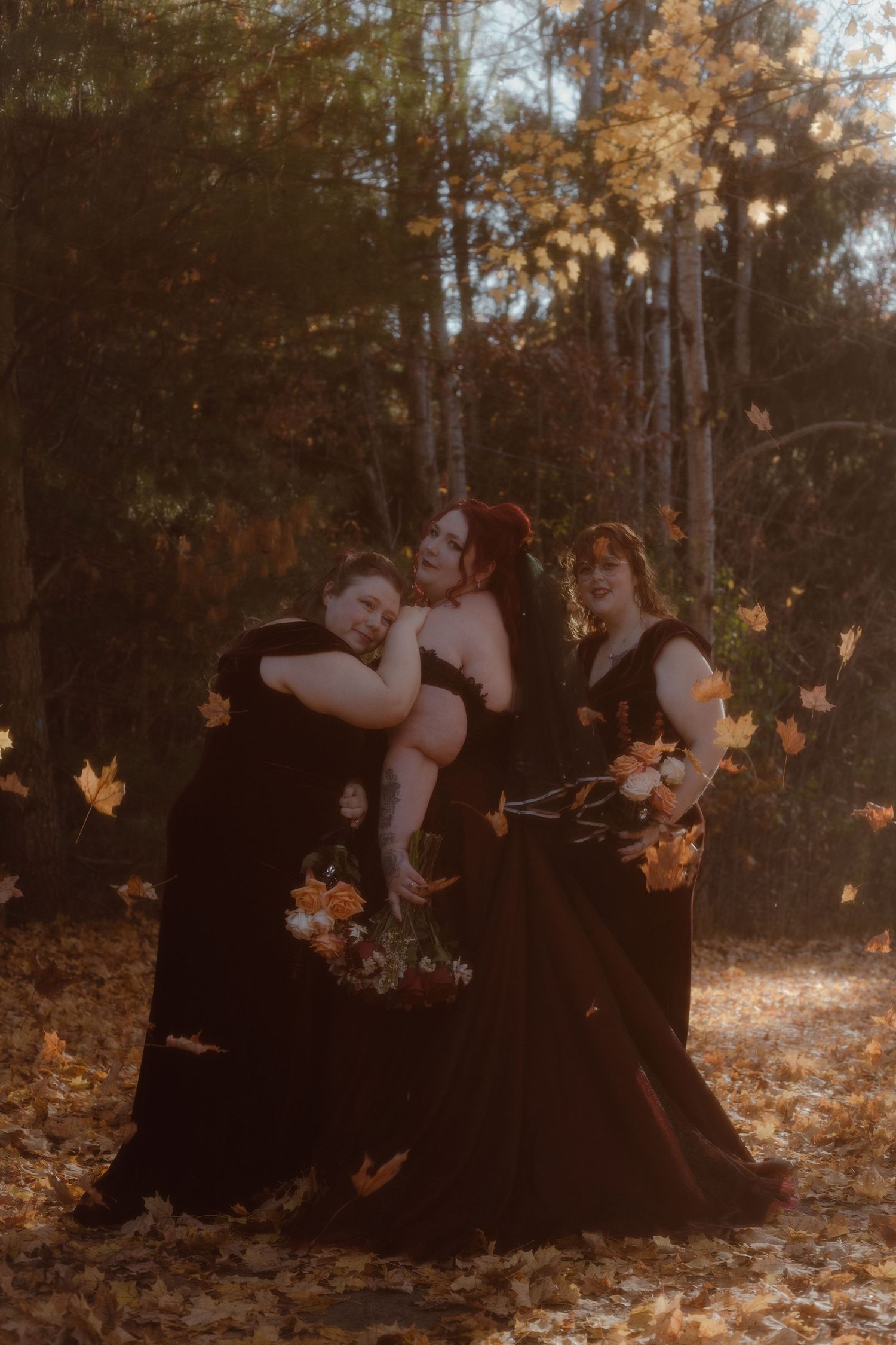 An alternative bride with her bridesmaids standing in front of a beautiful fall backdrop. A golden moment as the leaves are falling.