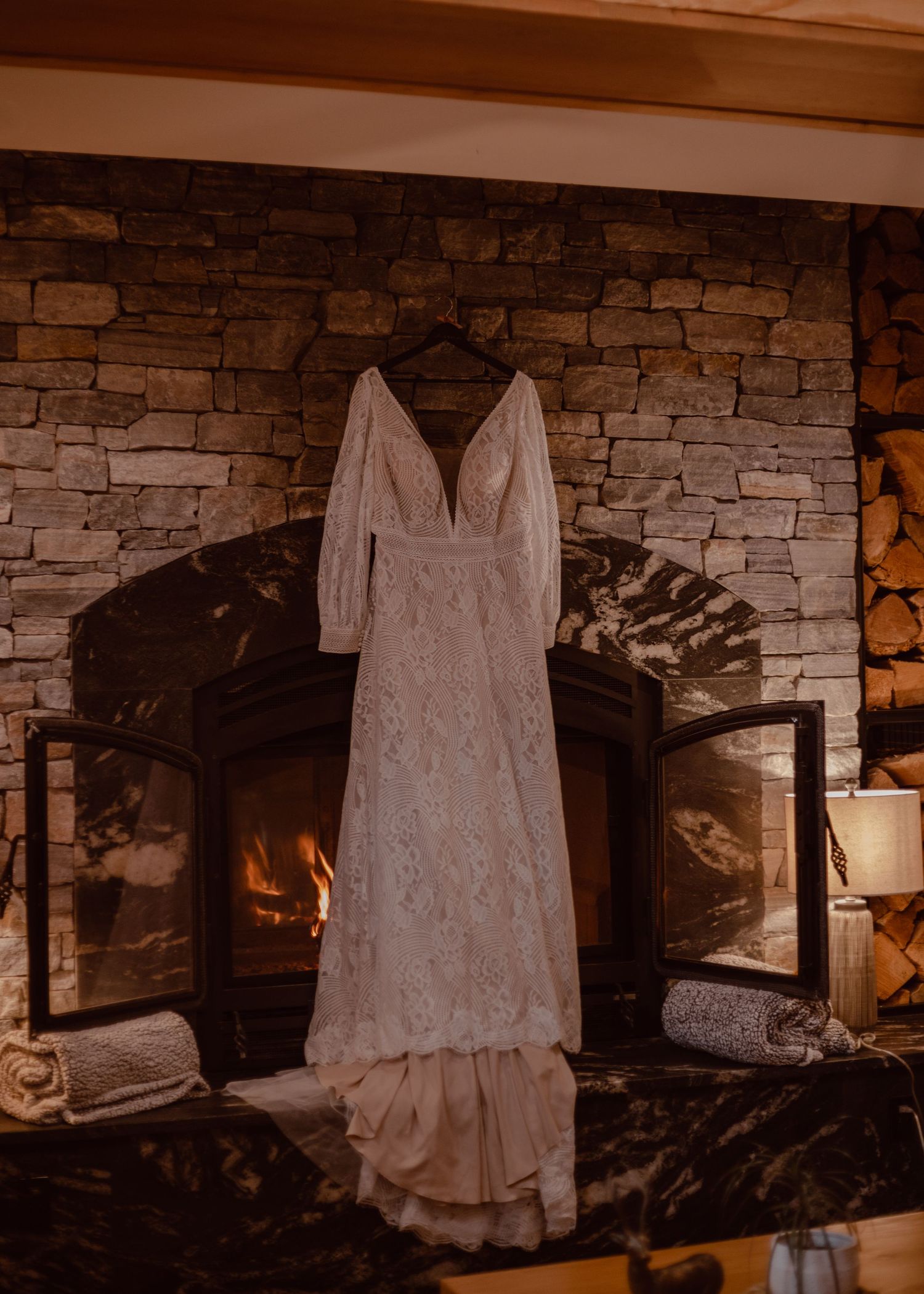 Detail shot of bride's dress hanging in front of the fireplace inside the hotel lobby.