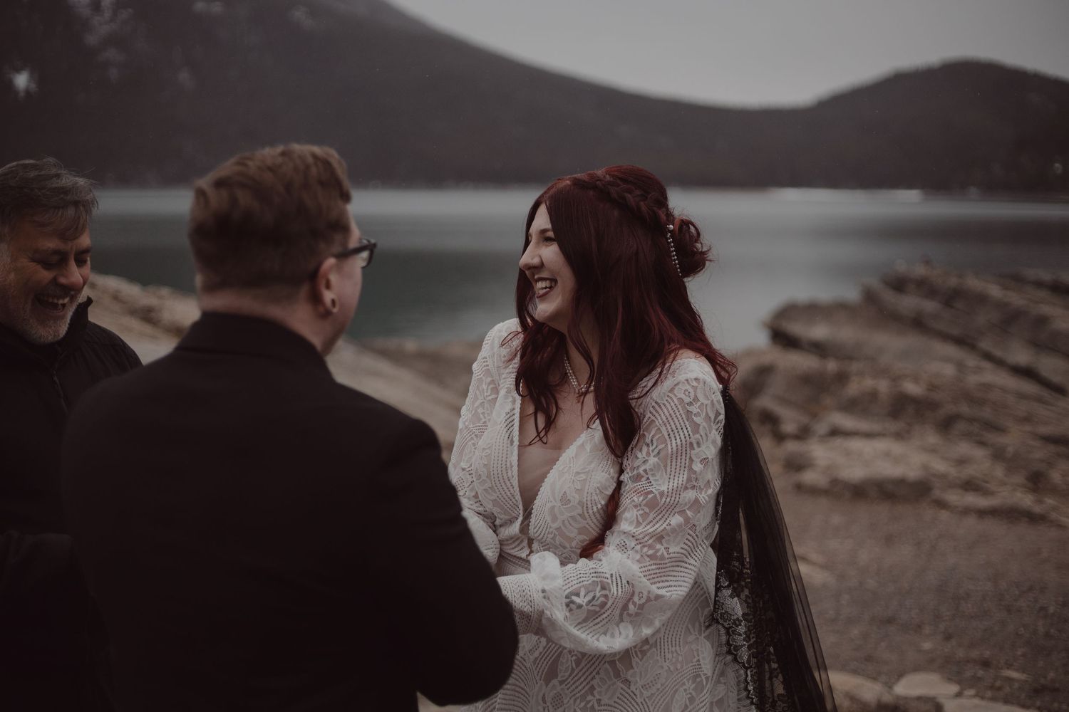 Bride smiling from excitement during groom's vows in front of a stunning lake in Banff.